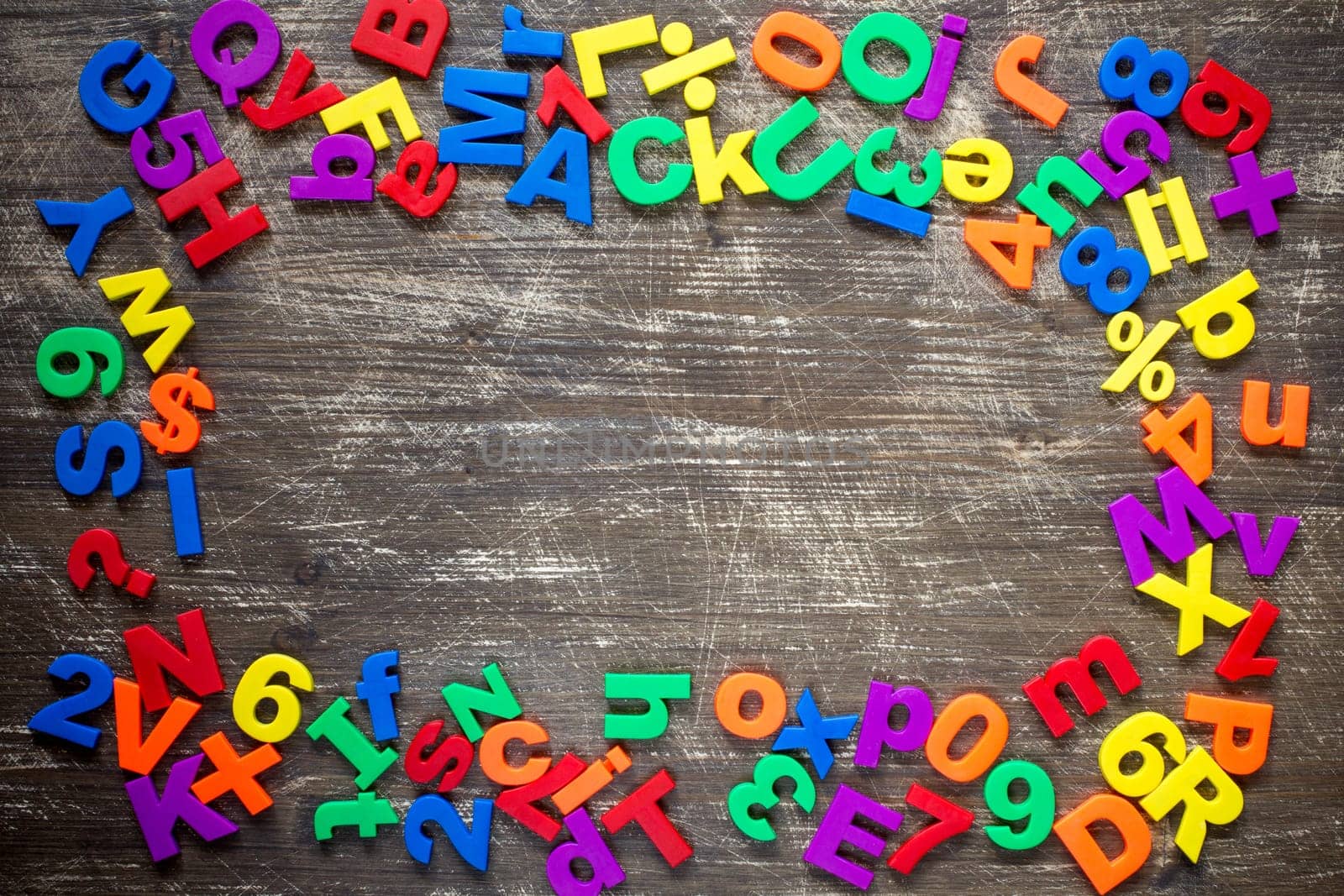 Top border of colorful  magnetic letters and numbers over a wooden background