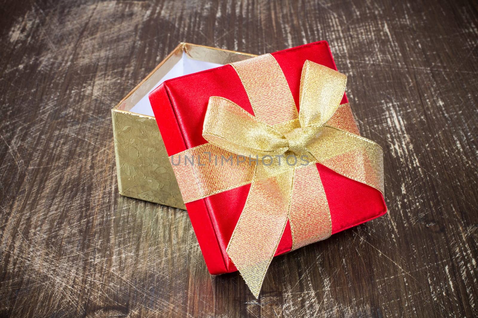 Open gift box with golden ribbon on the old wooden floor