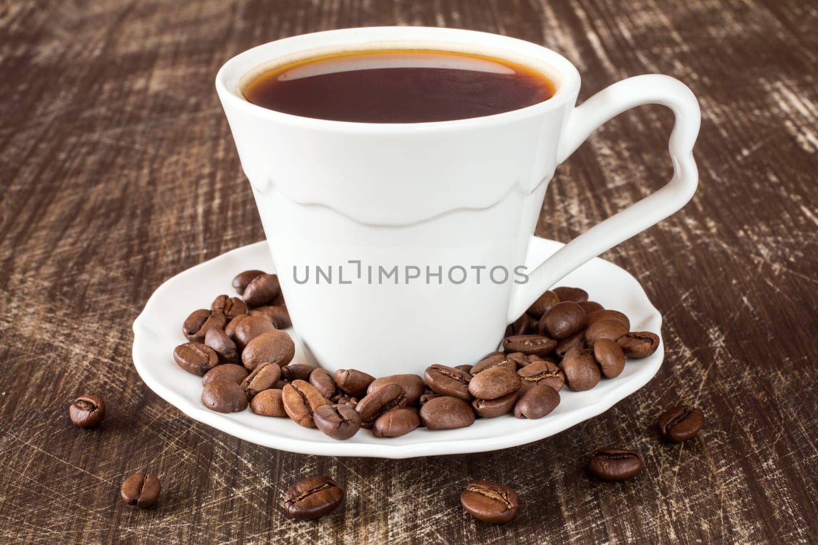White coffee cup with roasted coffee beans on wooden background.