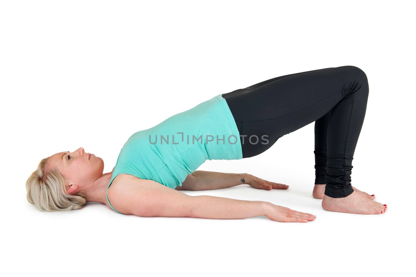 Full body view of a young blonde woman doing yoga exercises against a white background with a slight shadow
