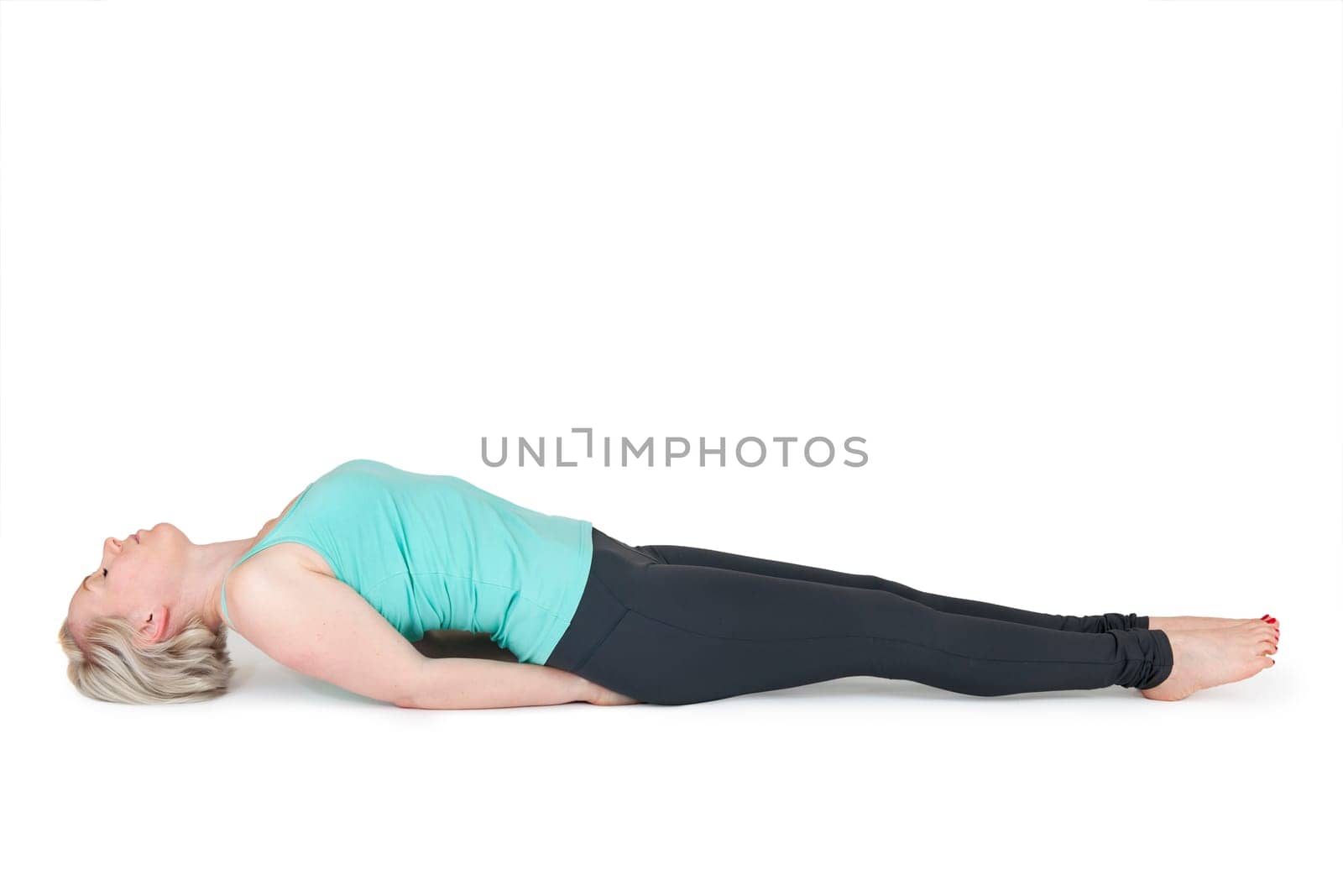 Full body view of a young blonde woman doing yoga exercises against a white background with a slight shadow