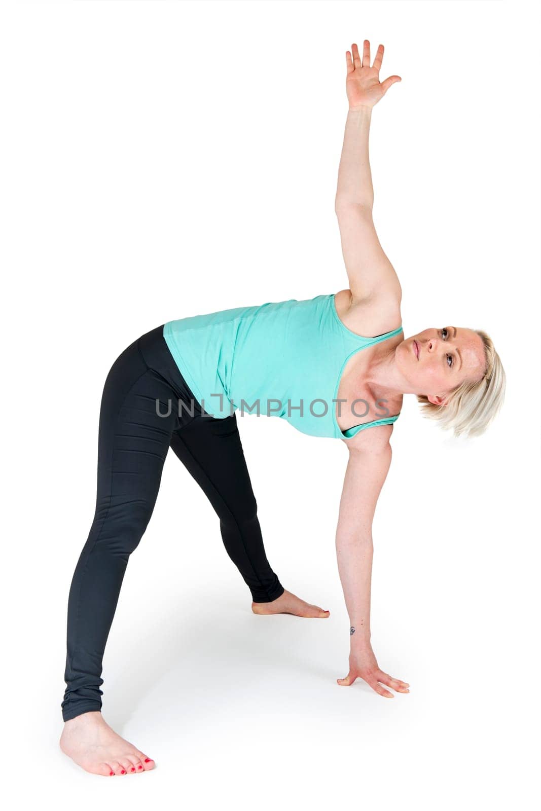 Full body view of a young blonde woman doing yoga exercises against a white background with a slight shadow