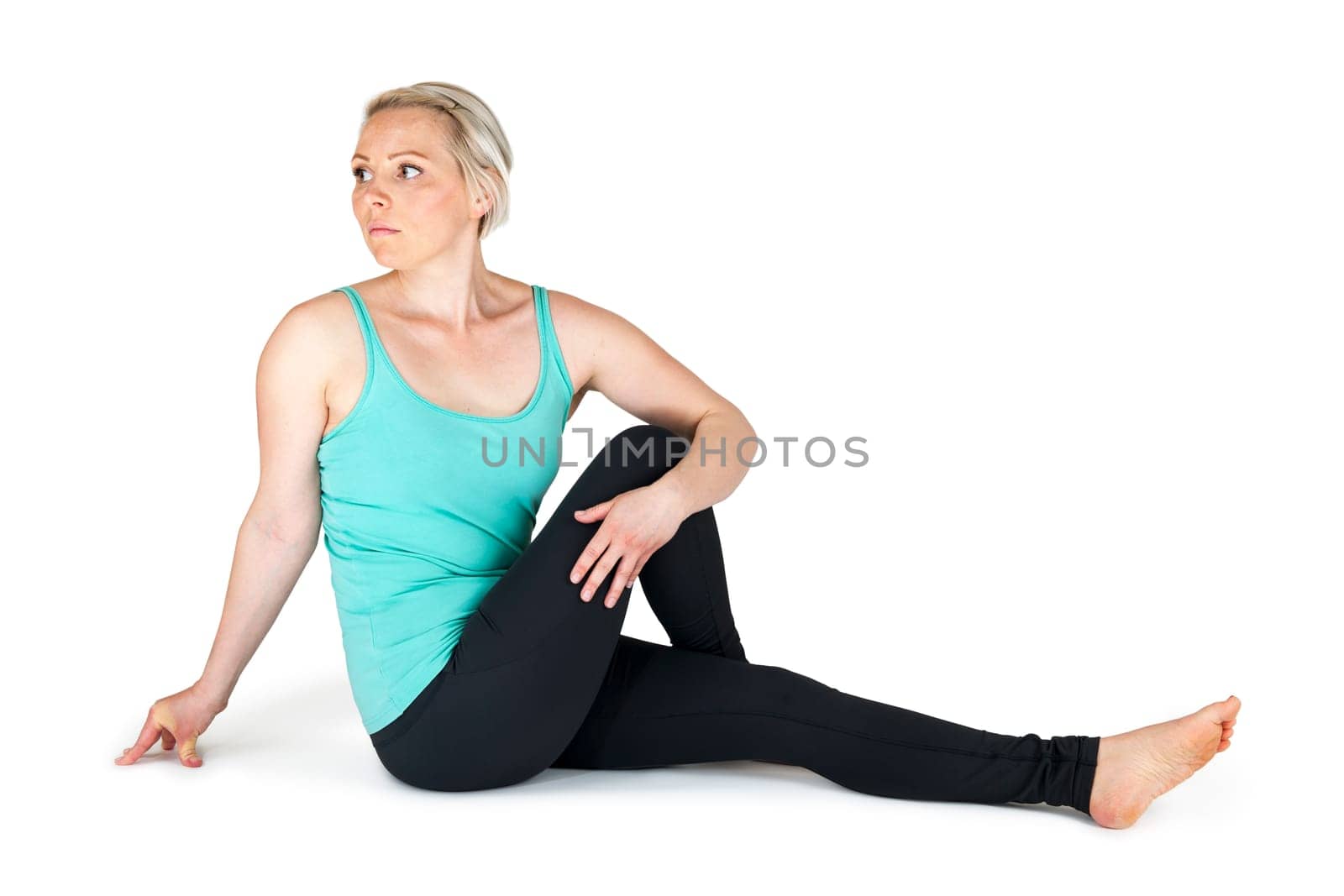 Full body view of a young blonde woman doing yoga exercises against a white background with a slight shadow