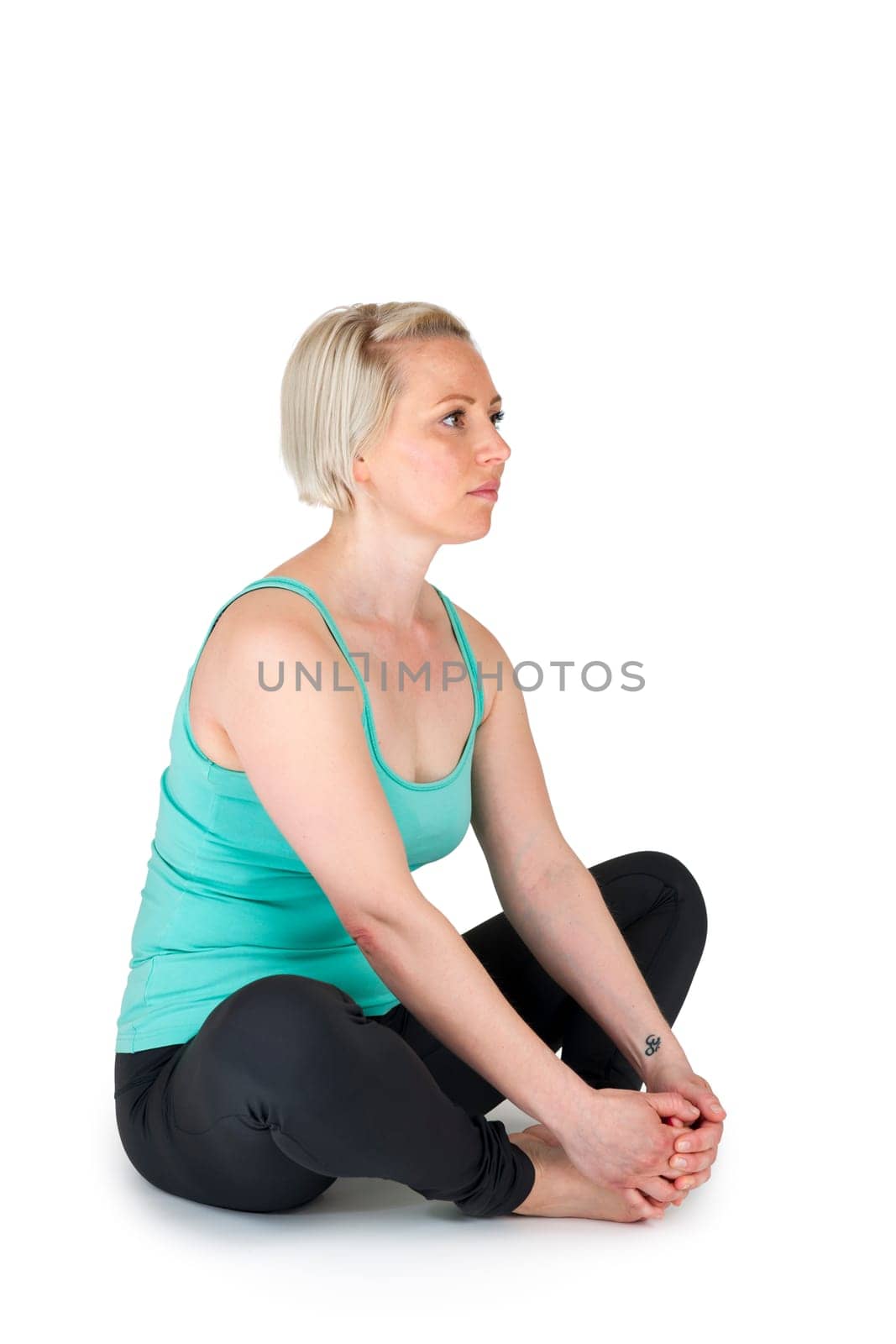 Full body view of a young blonde woman doing yoga exercises against a white background with a slight shadow