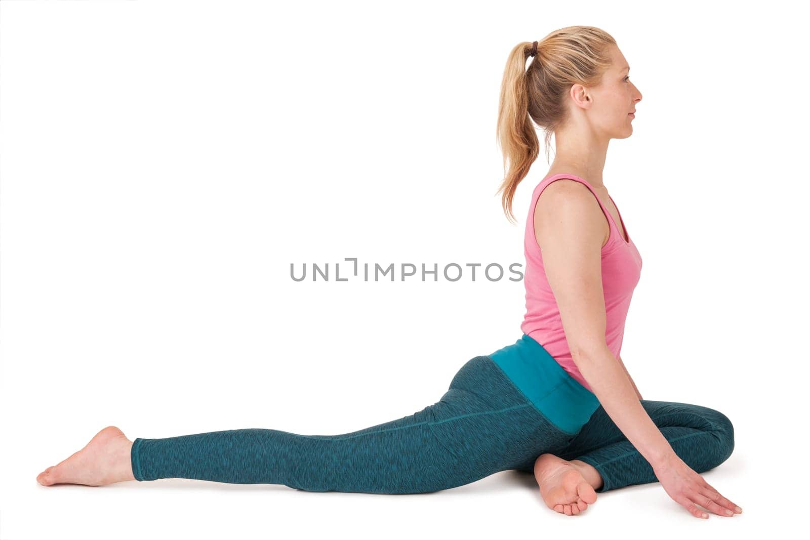 Full body view of a young blonde woman doing yoga exercises against a white background with a slight shadow