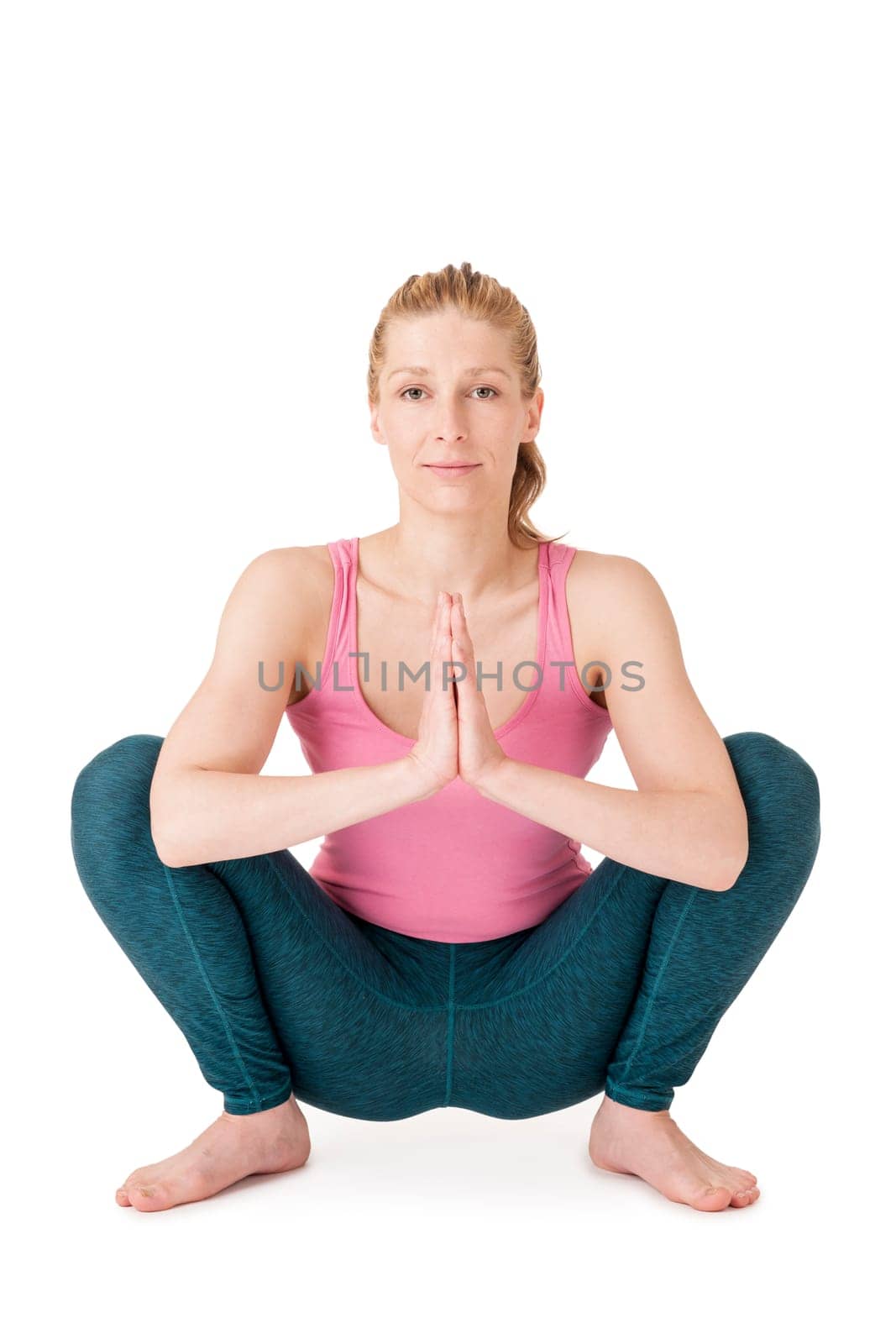 Full body view of a young blonde woman doing yoga exercises against a white background with a slight shadow