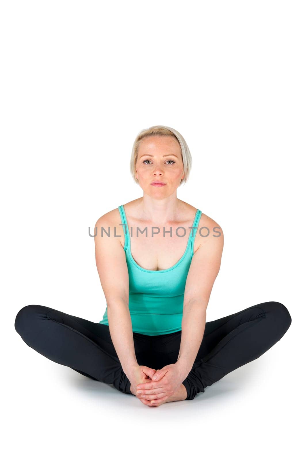 Full body view of a young blonde woman doing yoga exercises against a white background with a slight shadow