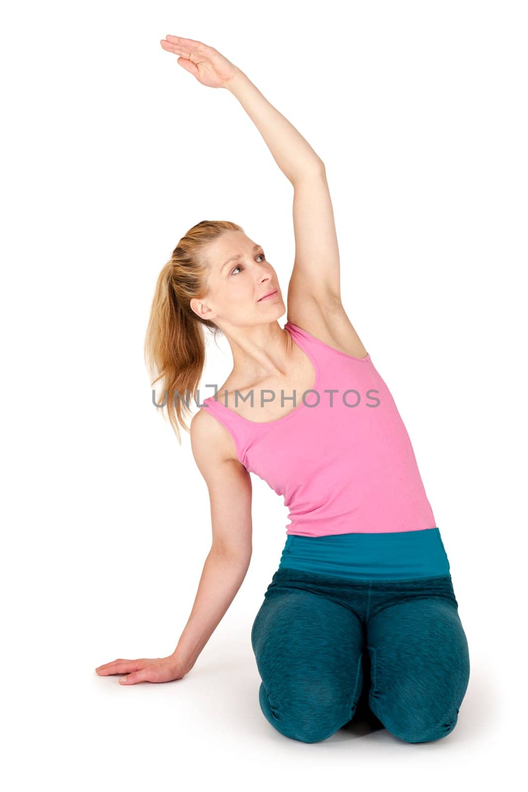 Full body view of a young blonde woman doing yoga exercises against a white background with a slight shadow