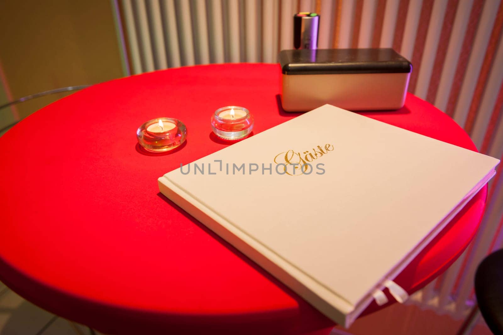 Close-up of a red round standing table with guest book and tealight