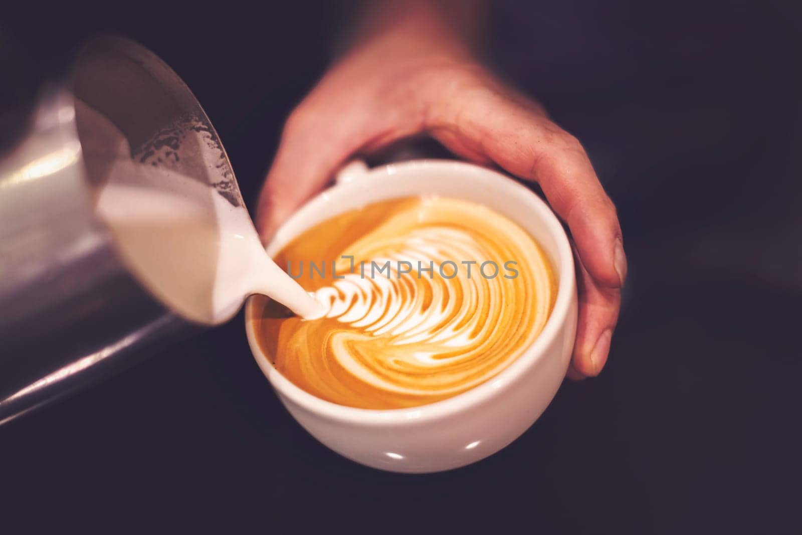 Barista pouring coffee into a cup creating beautiful pattern