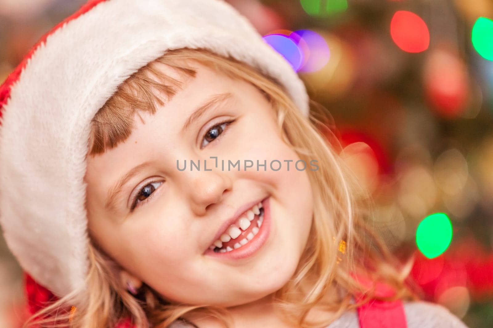 Cute Christmas girl with the Christmas tree lights bokeh in the background