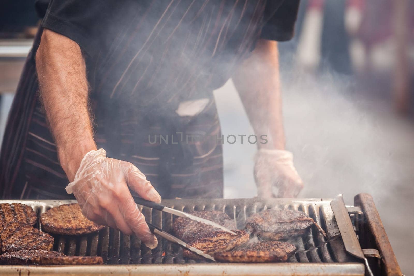 Chef  preparing burgers at the barbecue outdoors
