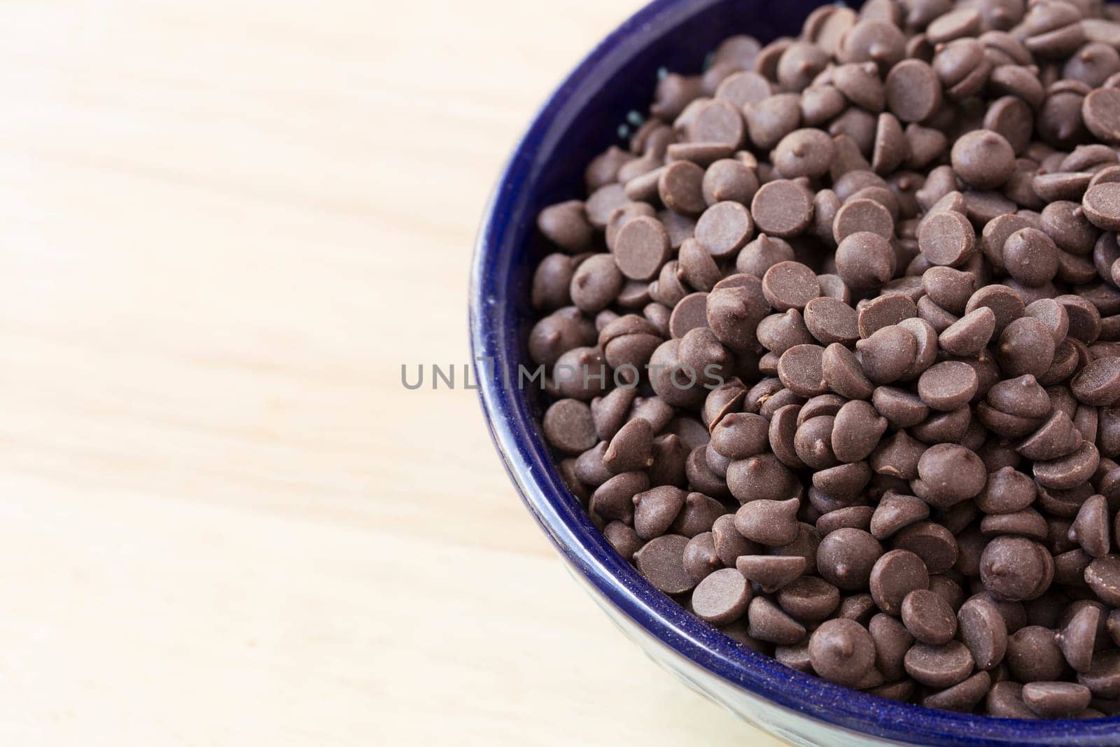 Chocolate chips in blue bowl close up with copy space