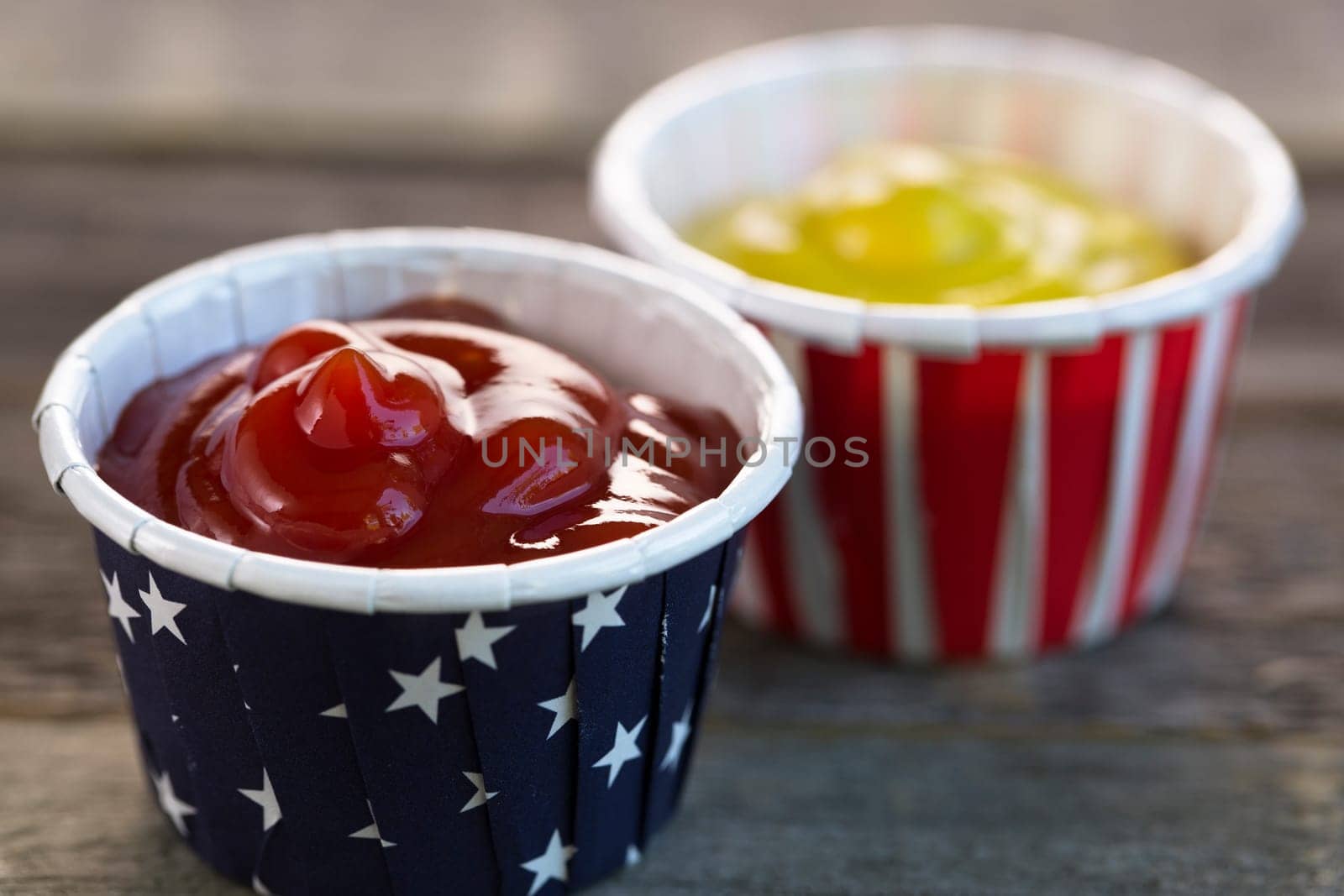 Ketchup and mustard in red white and blue paper cups ready for your BBQ