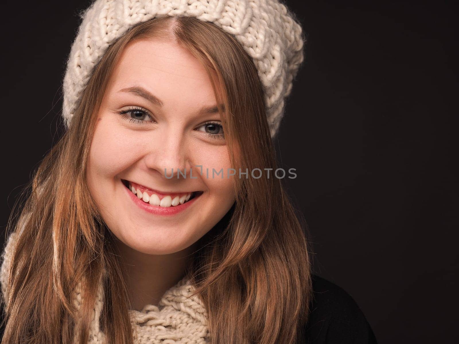 Attractive young woman with a wool cap on a dark background