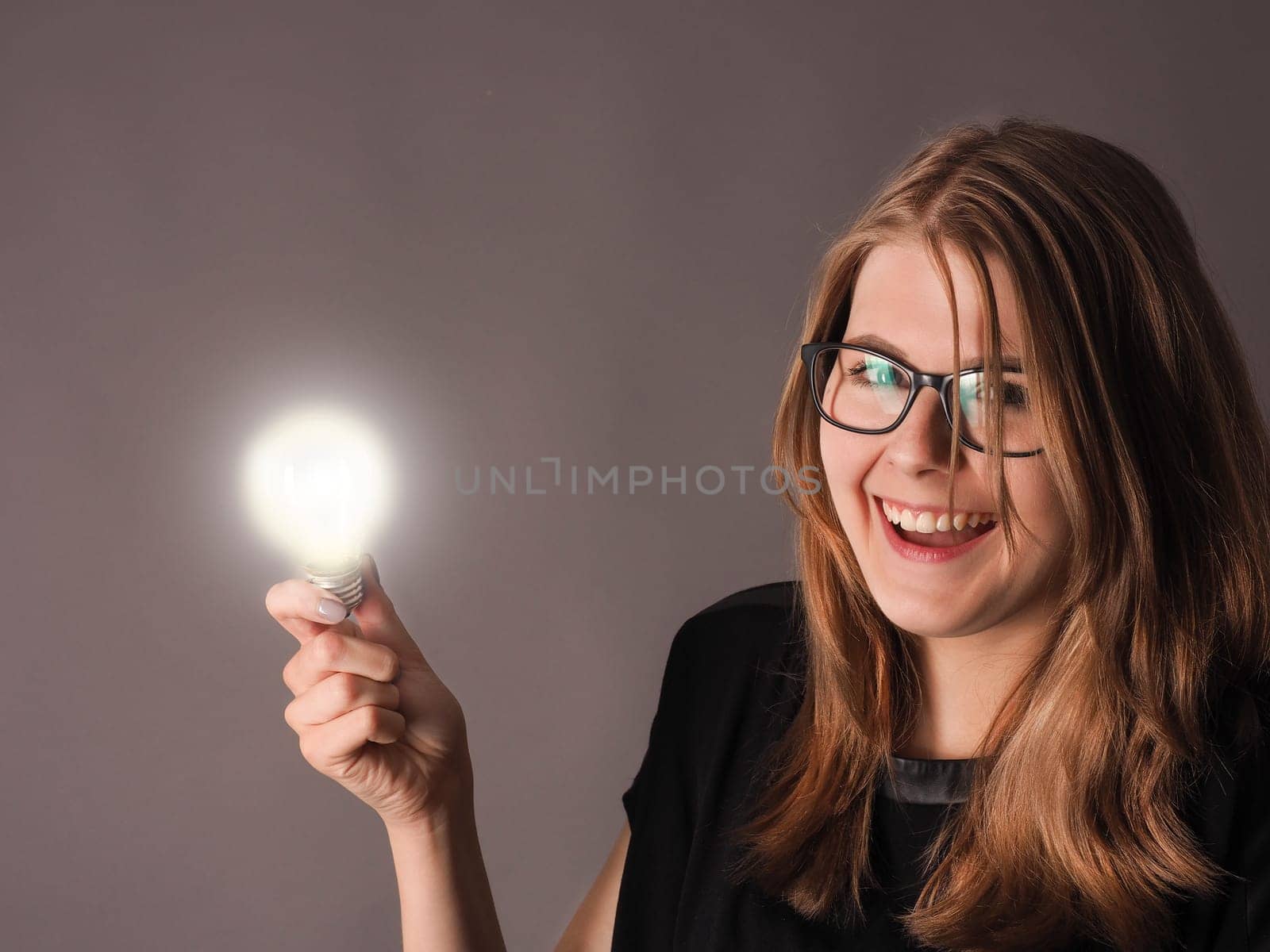 Cheerful female student with a glowing light bulb, great idea concept