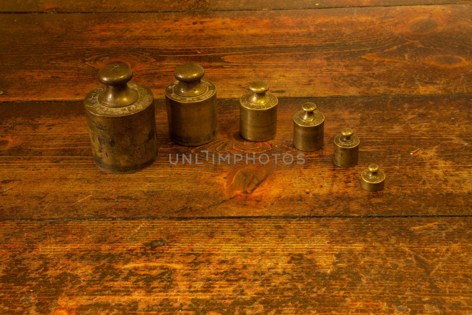 Different vintage brass weights unit on wood floor background