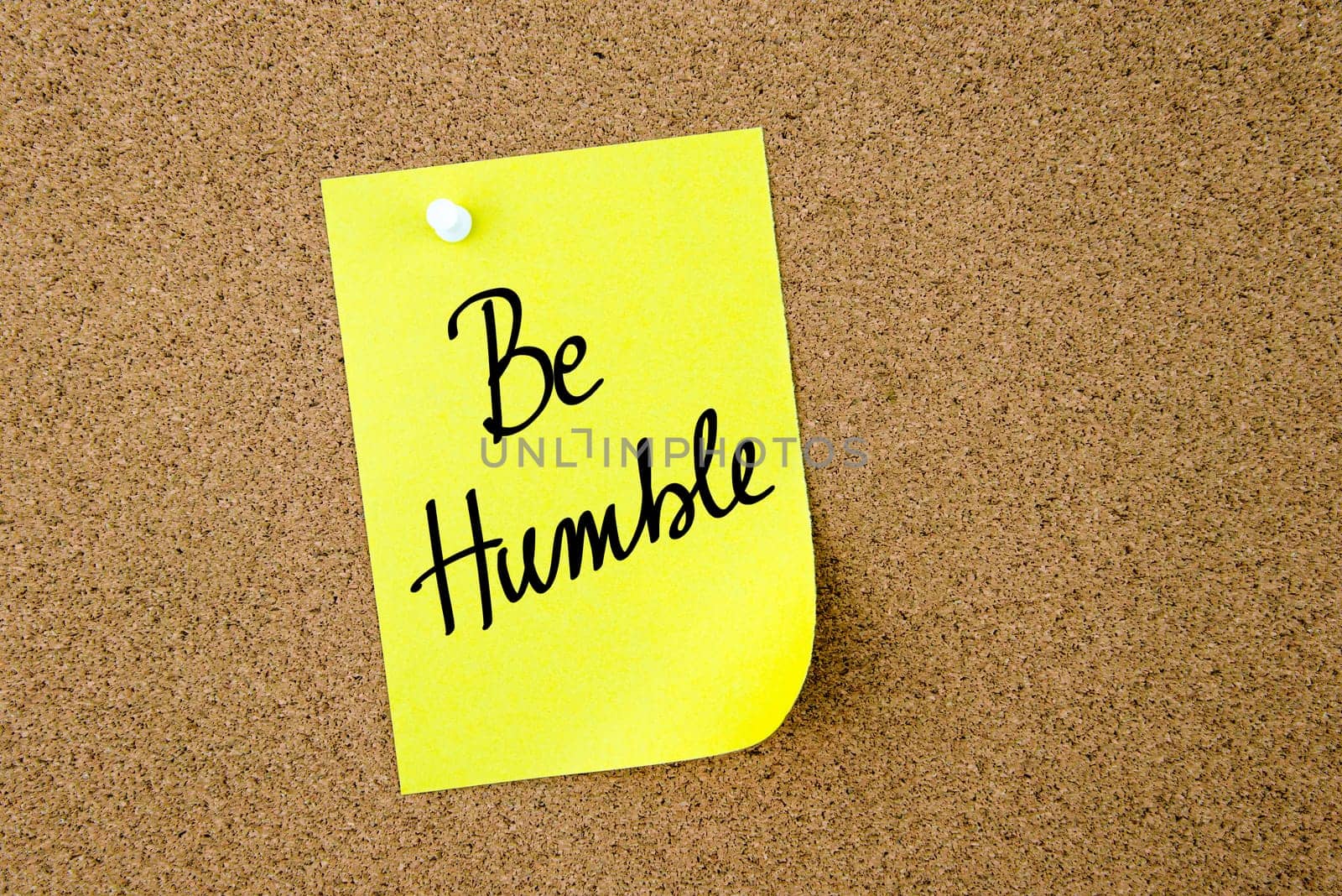 Be Humble written on yellow paper note pinned on cork board with white thumbtacks, copy space available