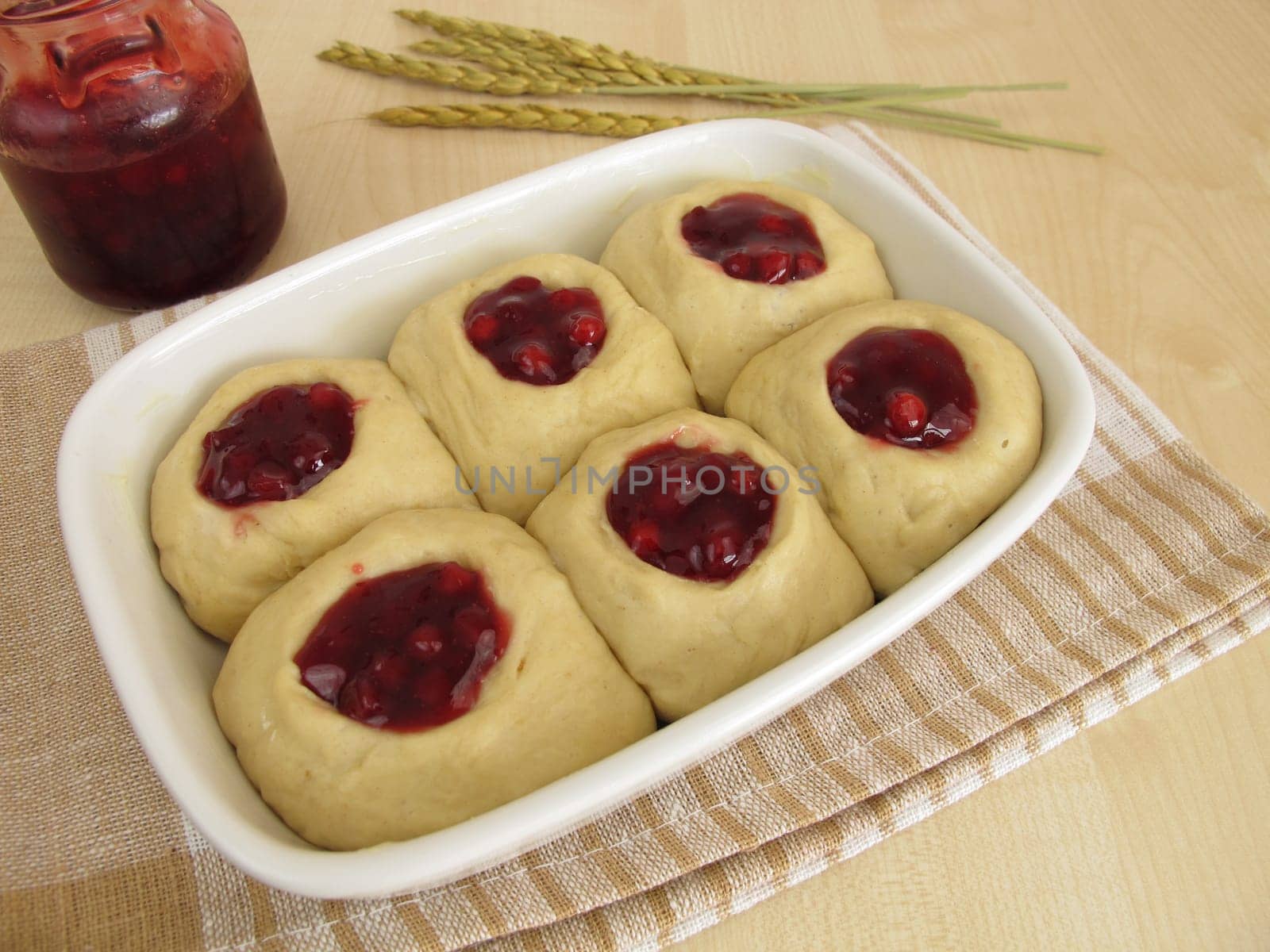 Raw yeast dough with cranberry jam in the baking pan for baking buchteln