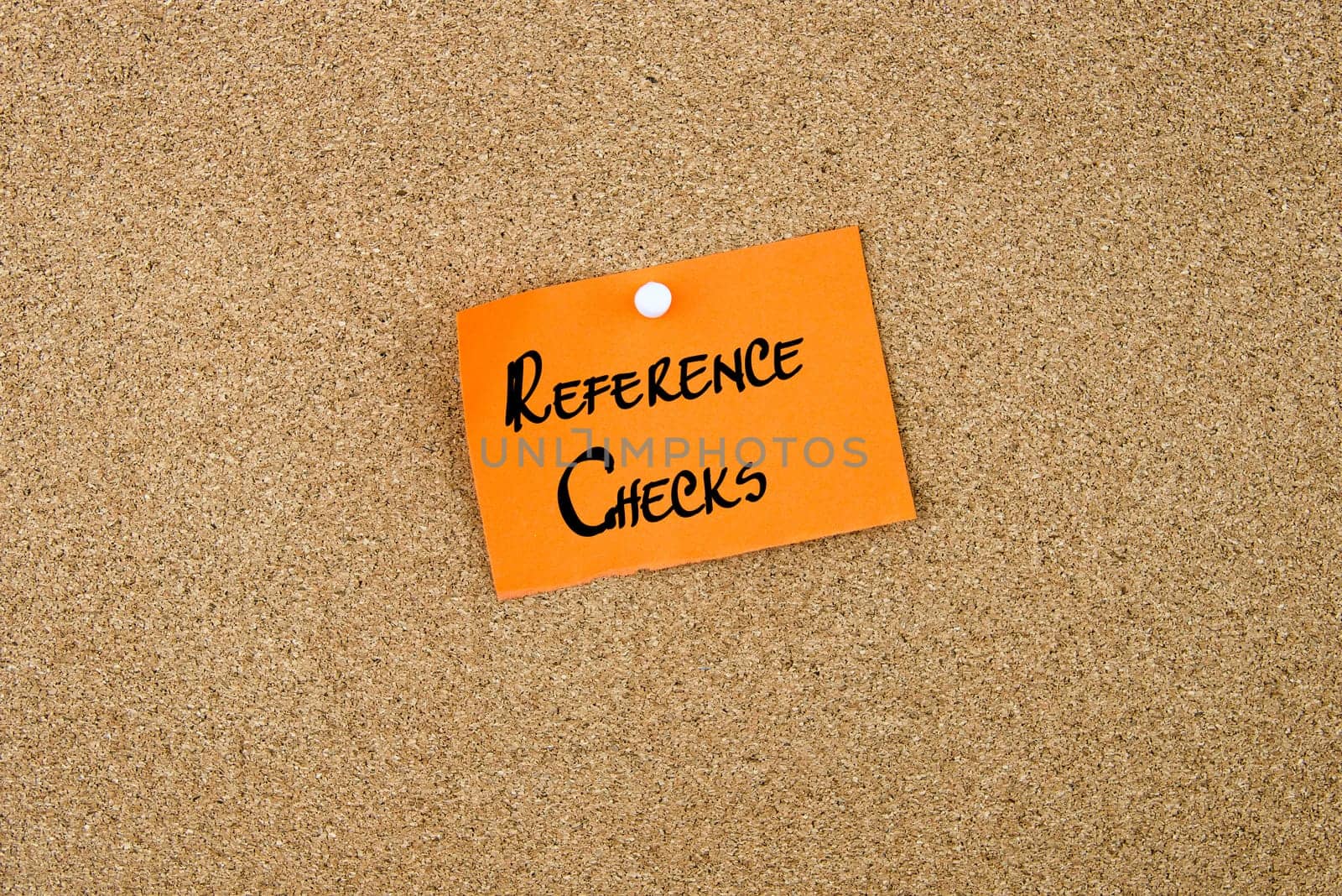 Reference Checks written on orange paper note note pinned on cork board with white thumbtack, copy space available