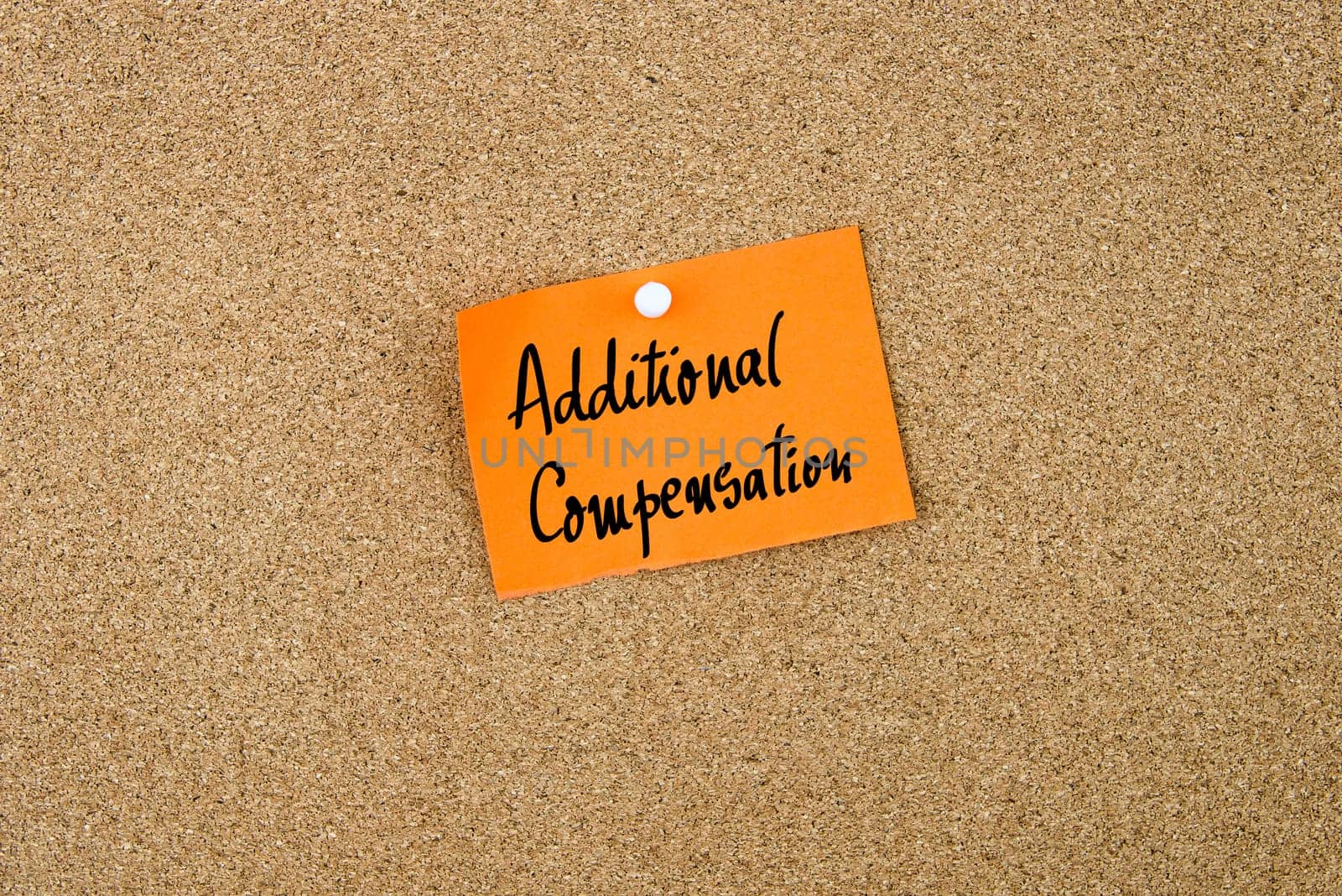 Additional Compensation written on orange paper note note pinned on cork board with white thumbtack, copy space available