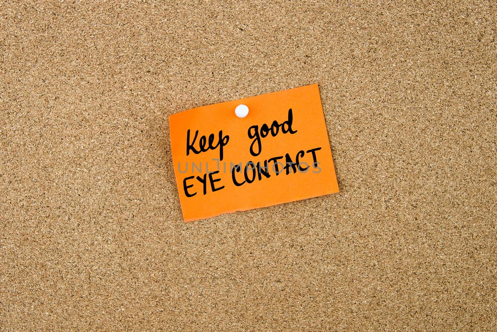 Keep Good Eye Contact written on orange paper note note pinned on cork board with white thumbtack, copy space available