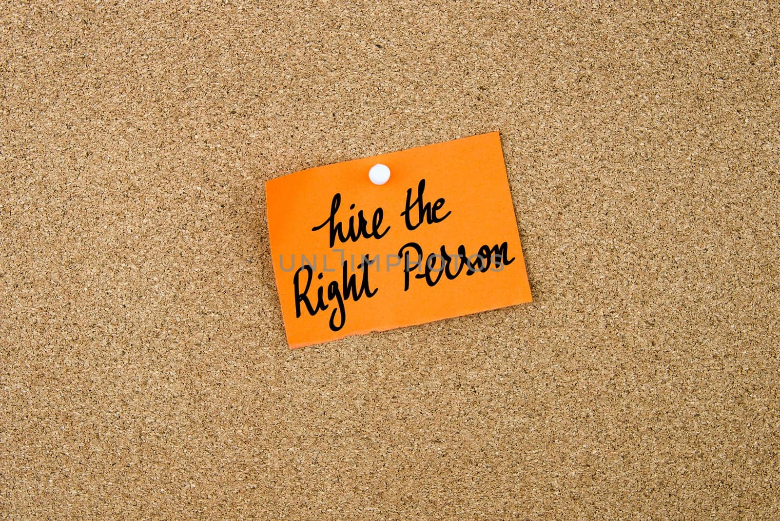 Hire The Right Person written on orange paper note note pinned on cork board with white thumbtack, copy space available