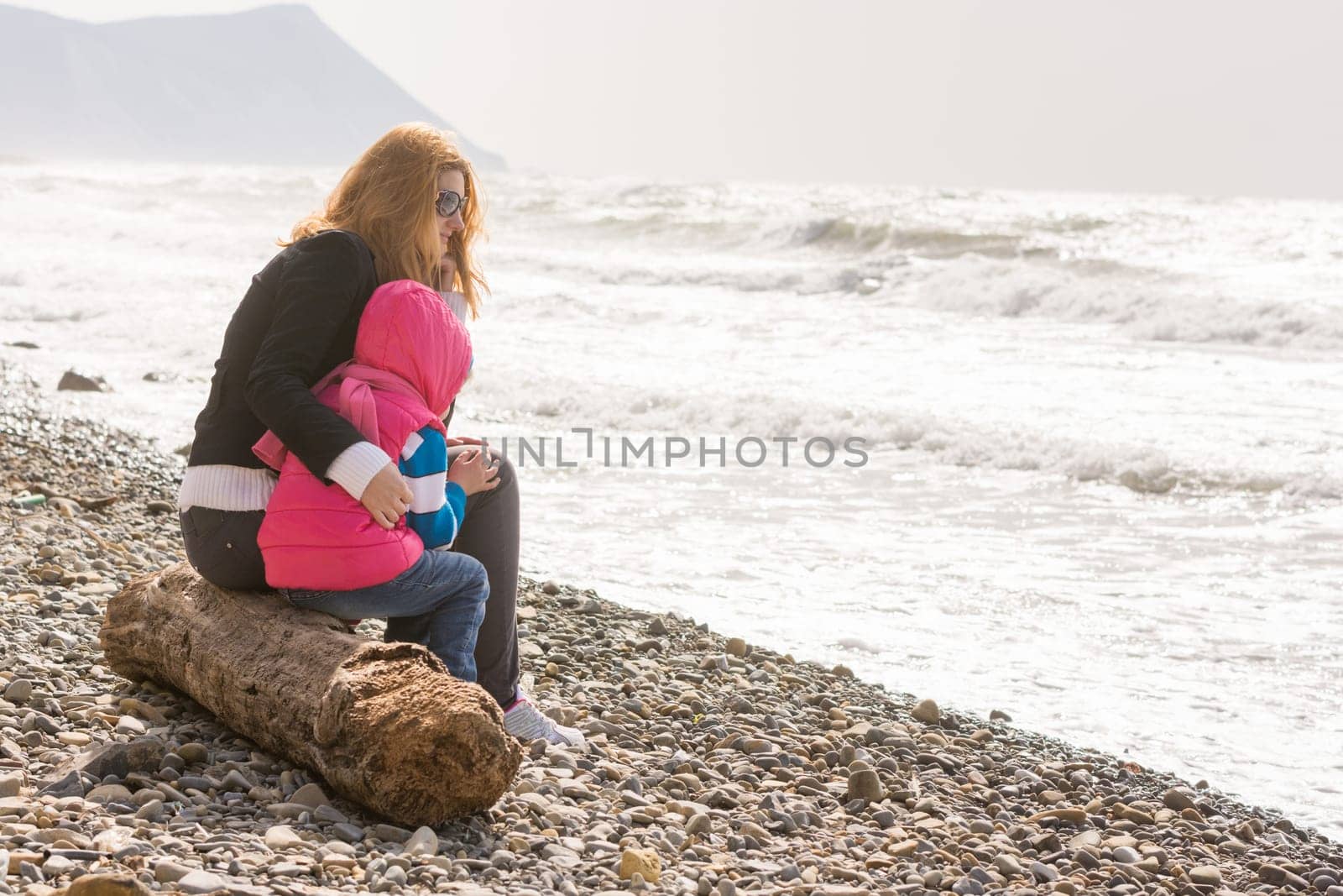 My mother and five year old daughter sitting on the beach, my mother hugged her frozen girl