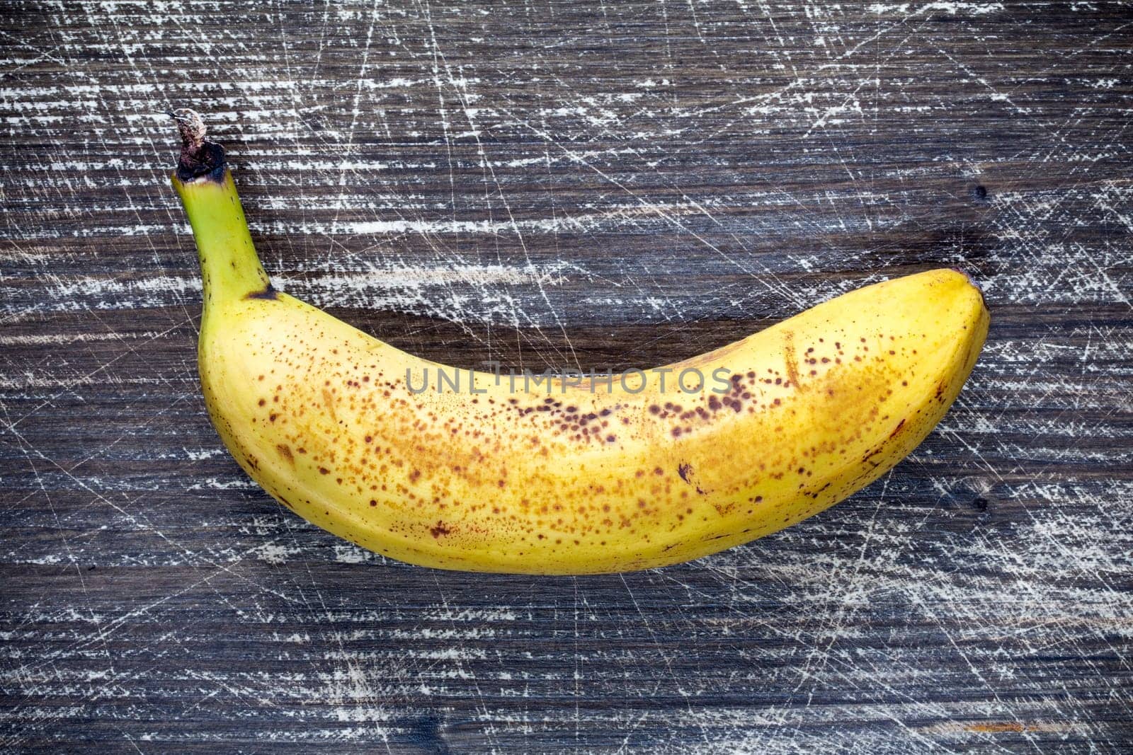Yellow banana on dark wooden background. Top view.