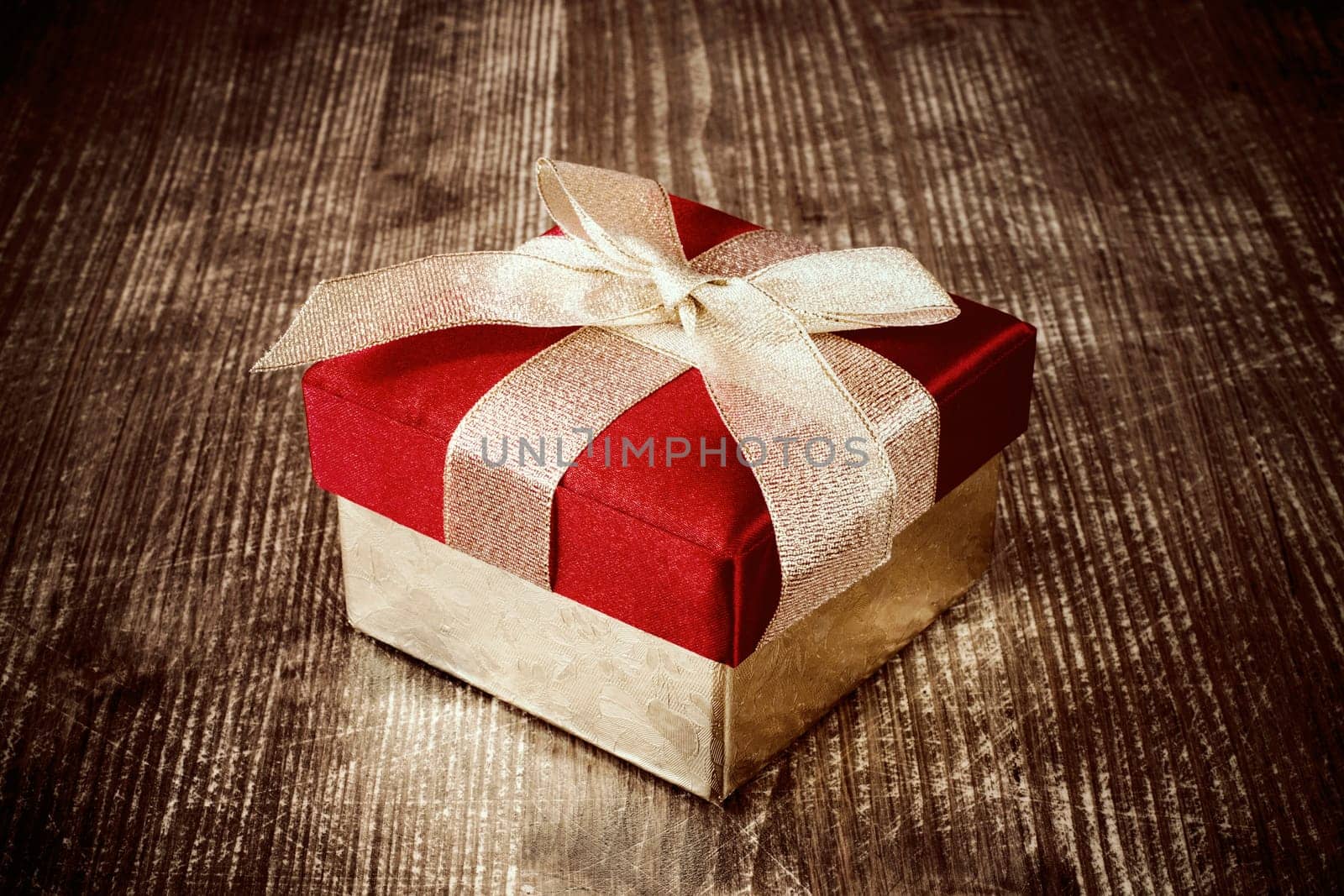 Gift box with golden ribbon on the dark wooden floor