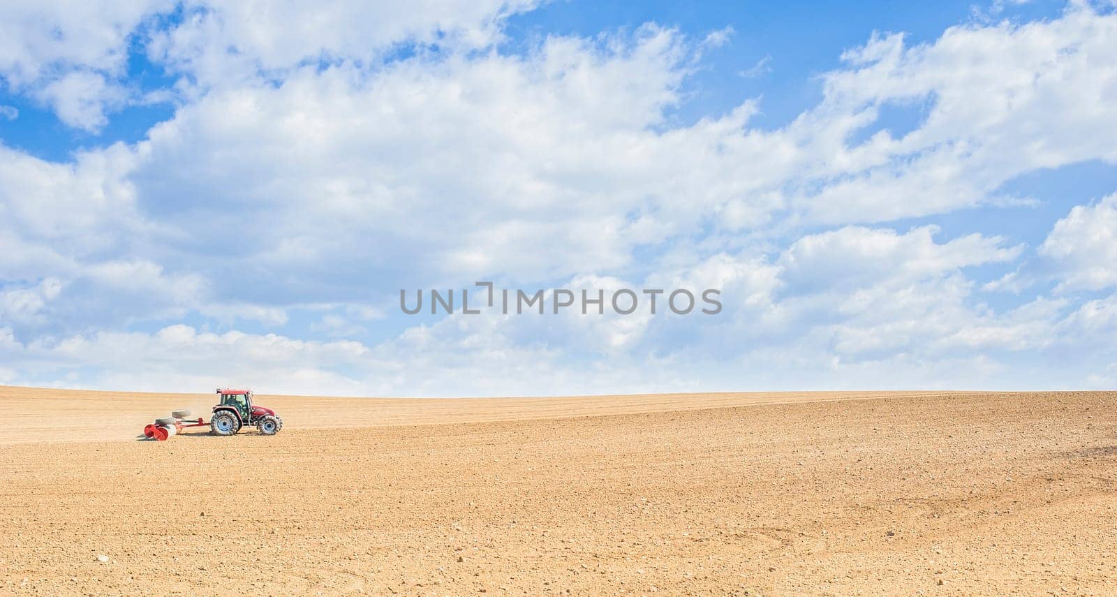 Farm work. Tractor compresses the soil after planting with rollers.