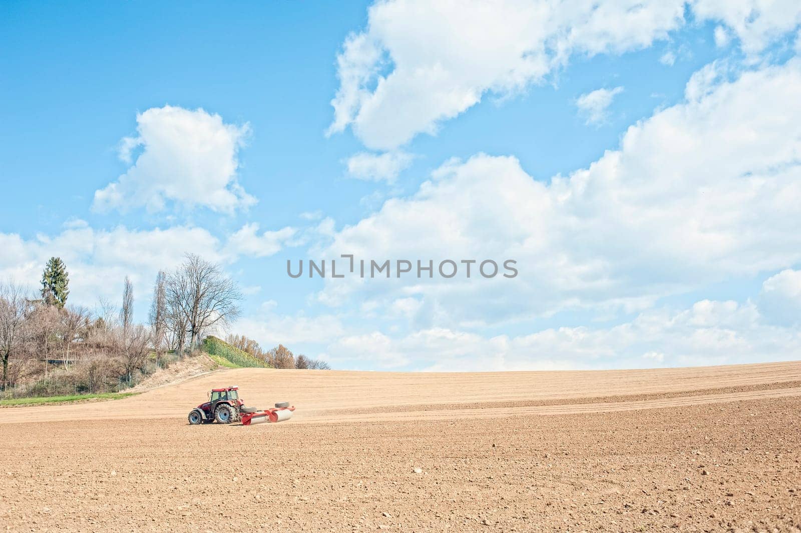 Farm work. Tractor compresses the soil after planting with rollers.
