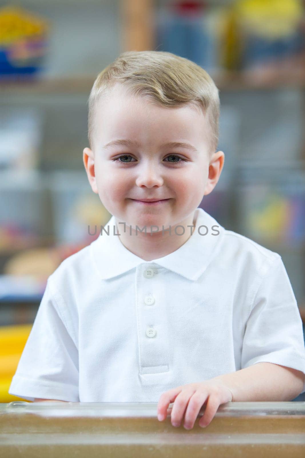 Portrait of a school boy. He is wearing a white shirt and smiling for the camera.