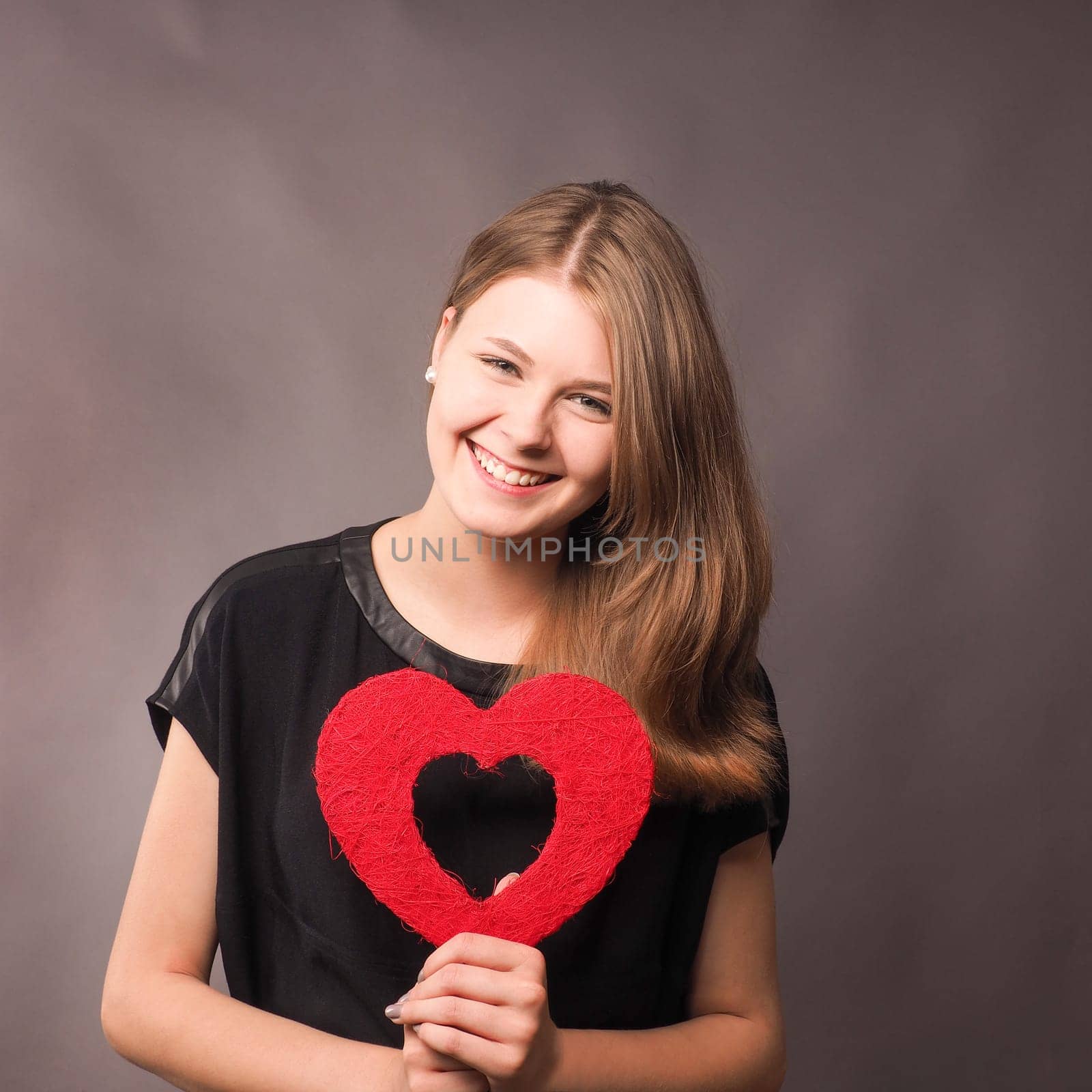 Happy young woman with a red heart shape, loving concept image