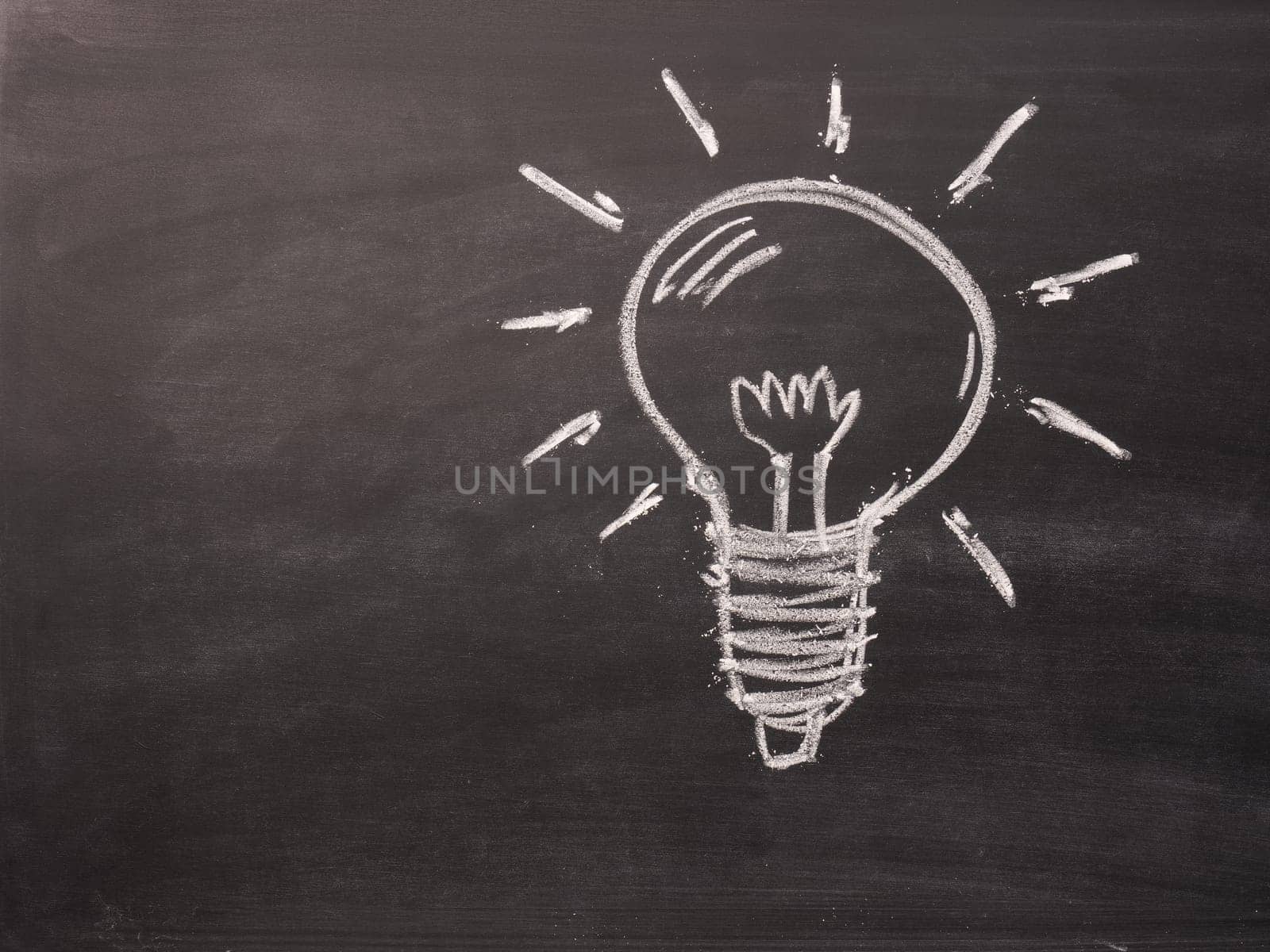 Hand drawing light bulb on a chalkboard with space for text