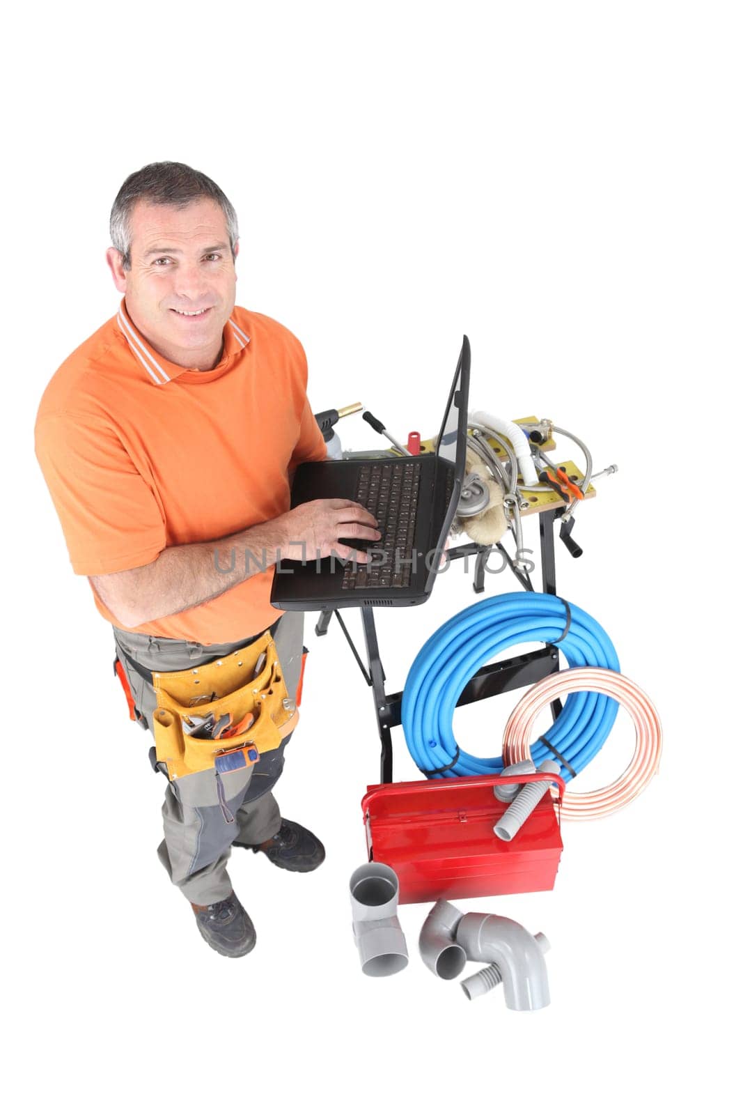 Workman posing with his laptop, tools and building materials