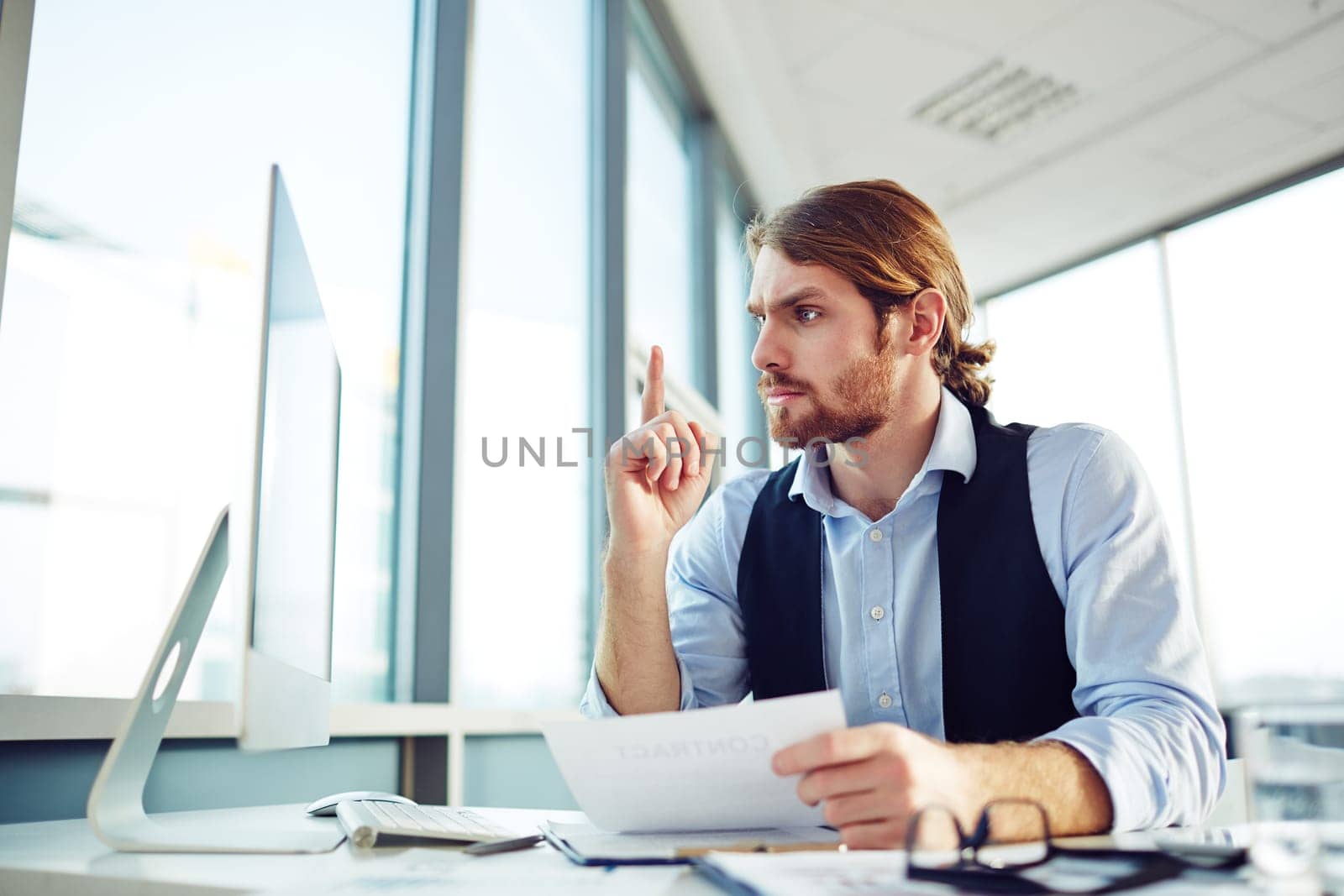 Young businessman looking at computer monitor with misunderstanding