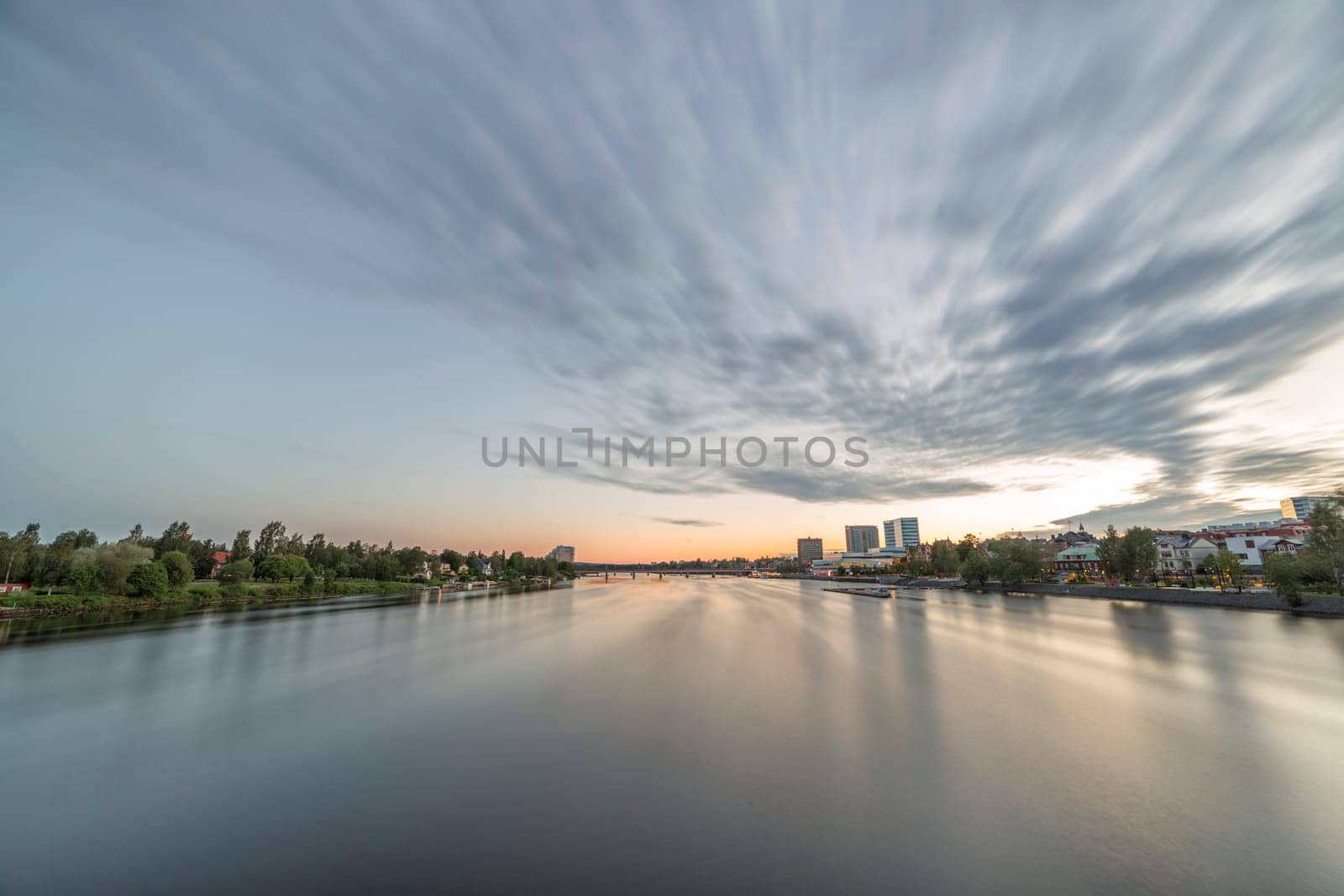 Downtown Umea, Sweden and its river with a cloudy sky at sunset.
