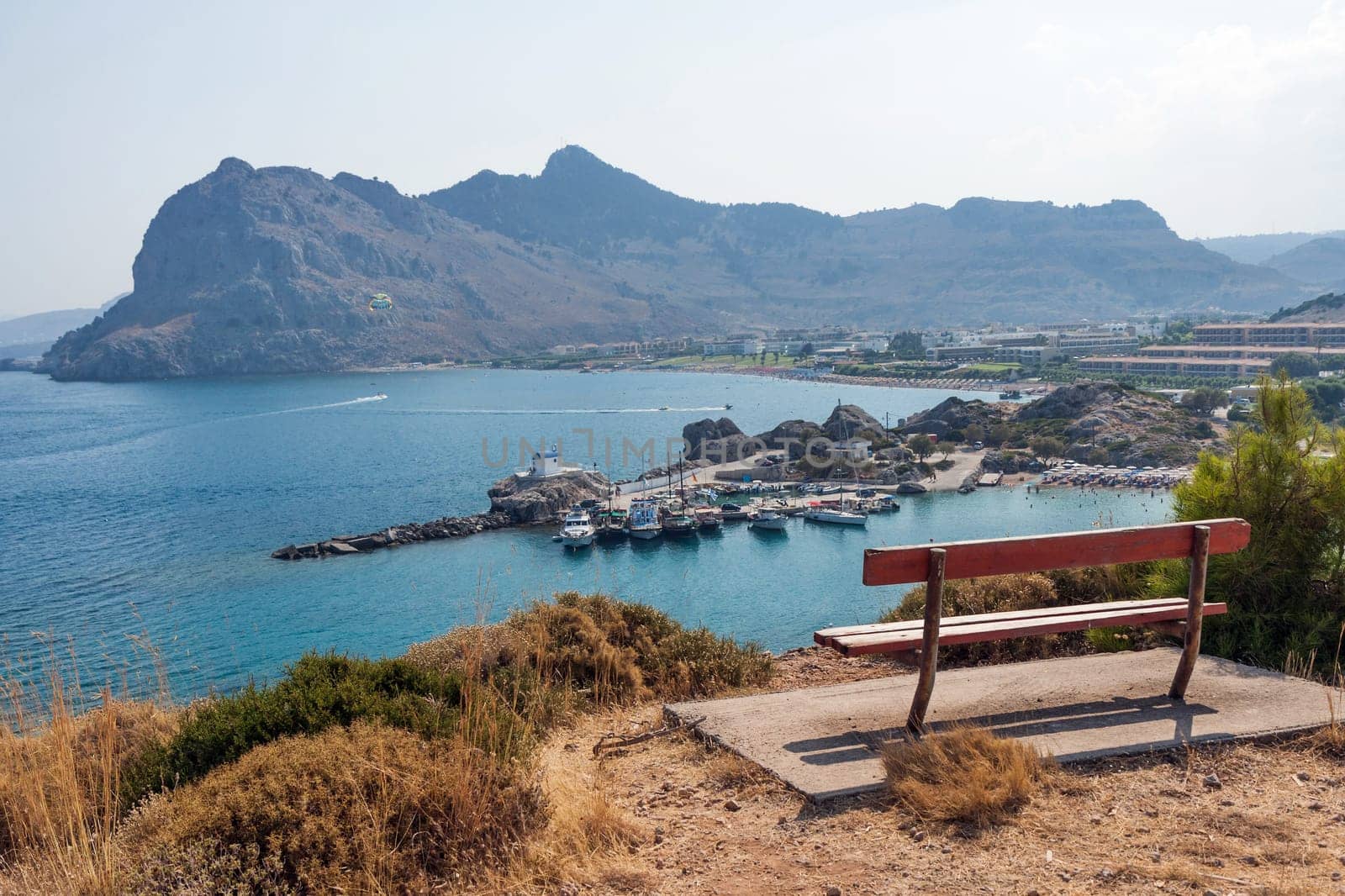 Kolymbia beach with the rocky coast in Greece. Empty bench on the island of Rhodes. View of the coast in Kolympia
