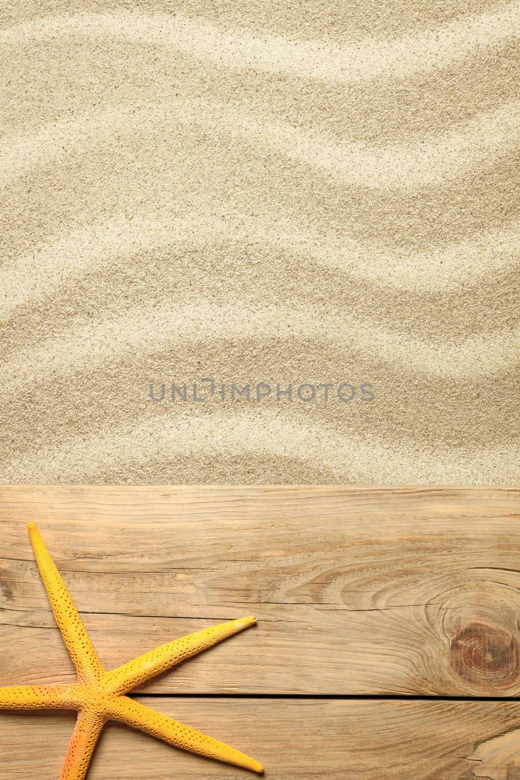 summer concept with yellow starfish on planks and sandy beach