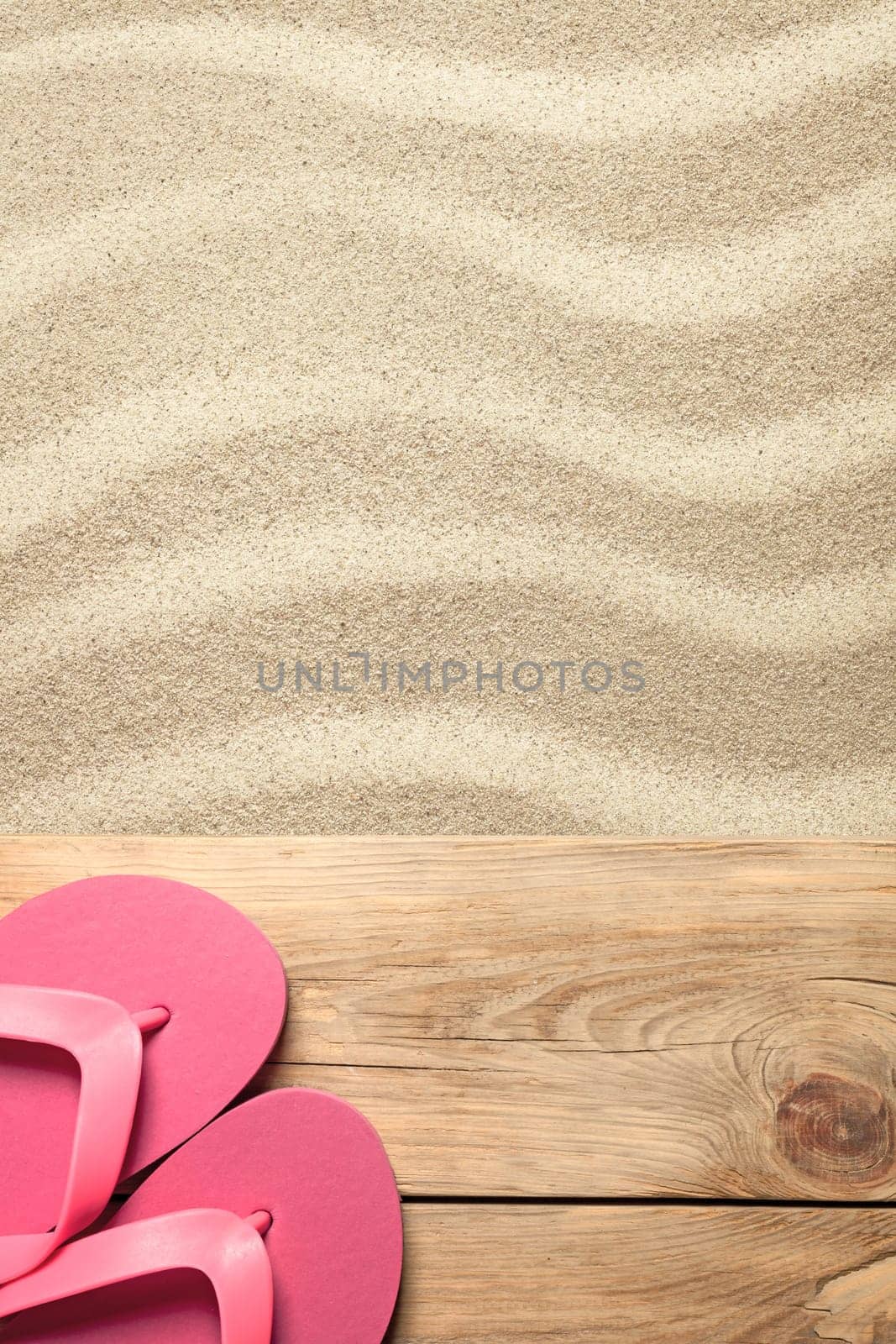 summer concept with pink flip flops on sandy beach