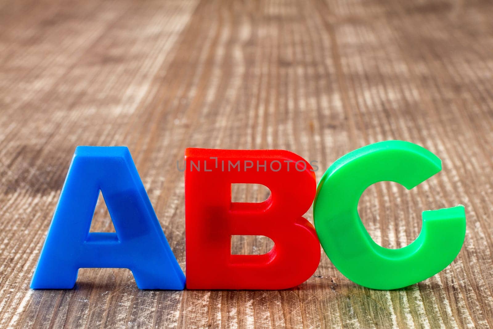 ABC spelling  of colorful plastic letters on wooden background