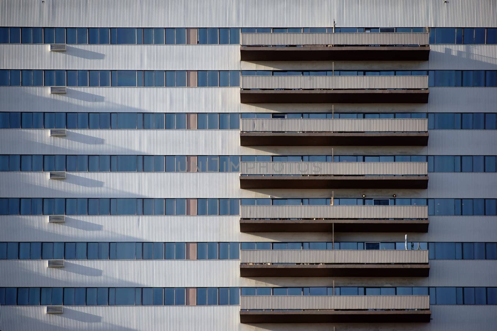 The high-rise façade of a residential and commercial building with symmetrically arranged balconies.