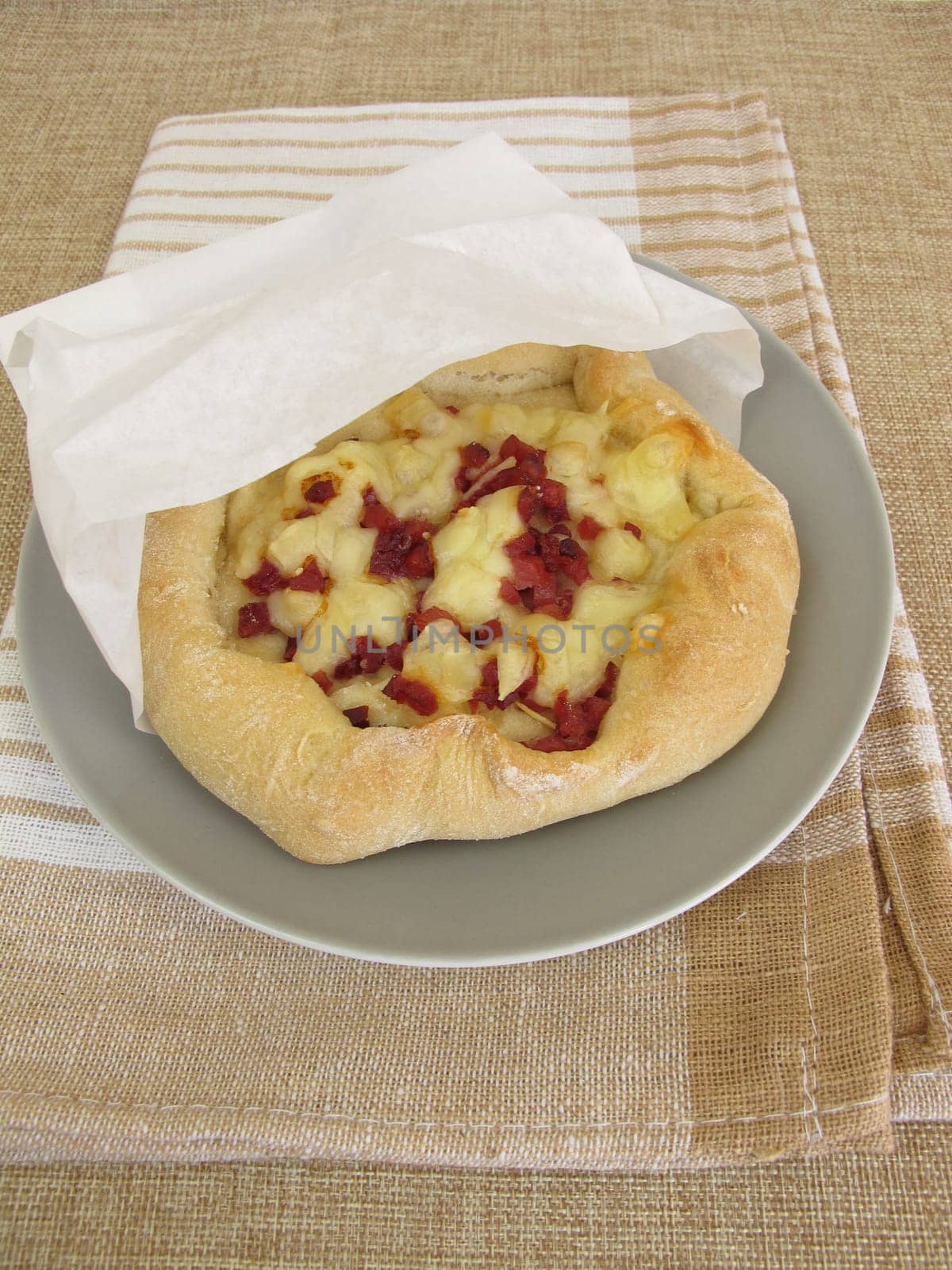 Pizza bread street food with cheese and ham in a sandwich paper bag