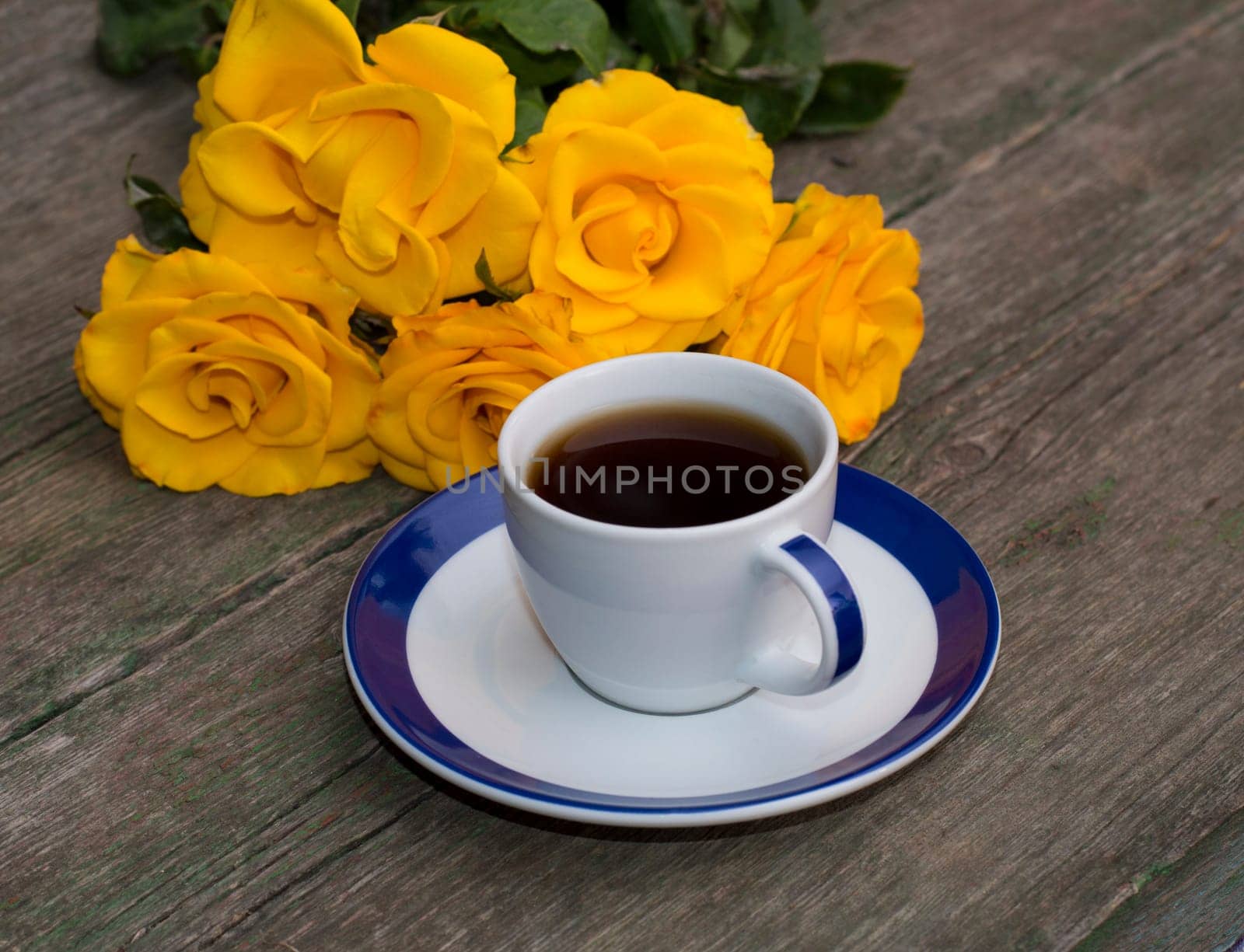 cup of coffee and yellow flowers on an old table