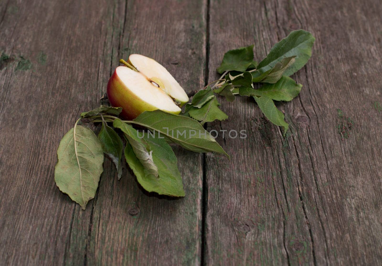 the cut apple with leaves on an old wooden table, a subject fruit