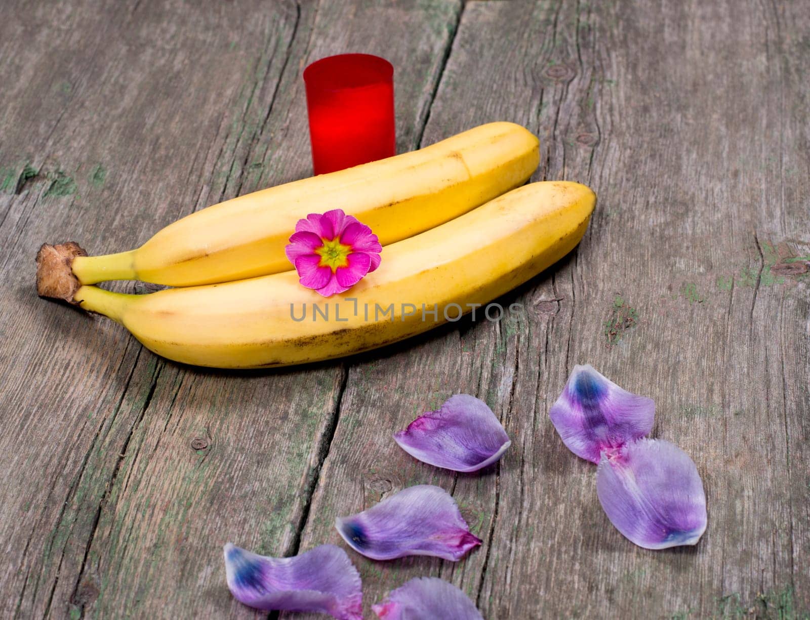 two bananas the decorated with lilac petals and red candle, a subject fruit