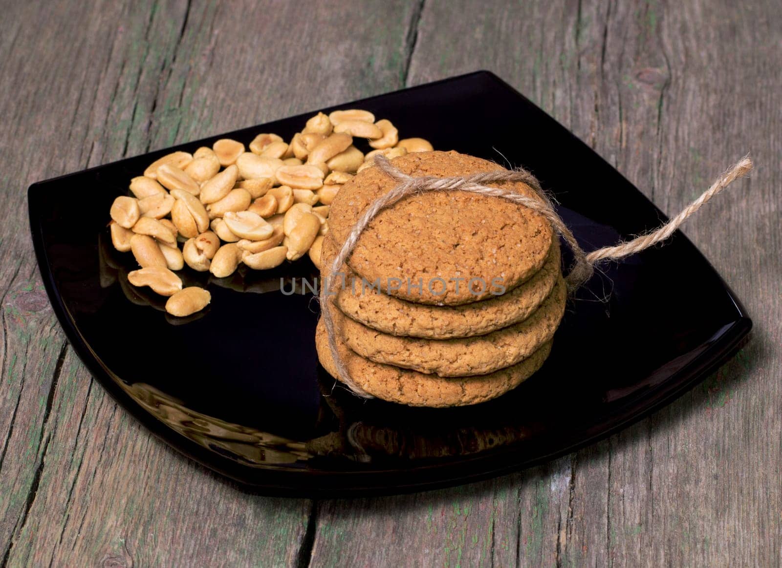 black plate with a peanut and oatmeal cookies, a sweet subject