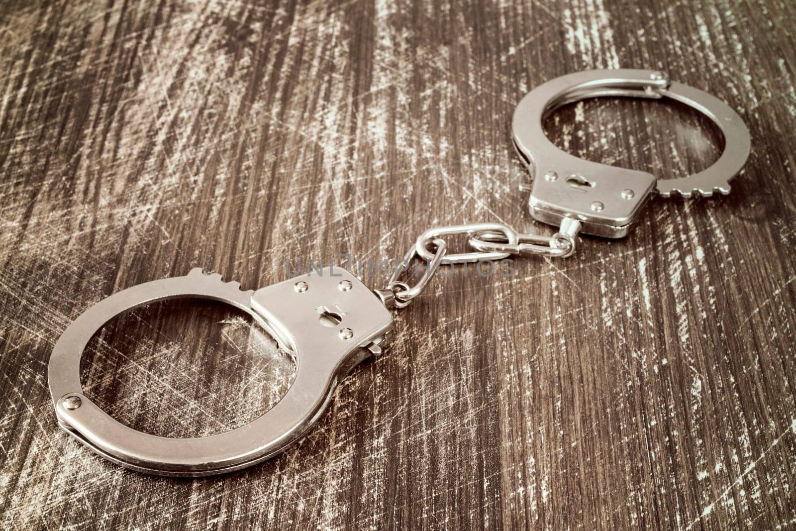 Close-up view of handcuffs on the wooden background.Filtered image.