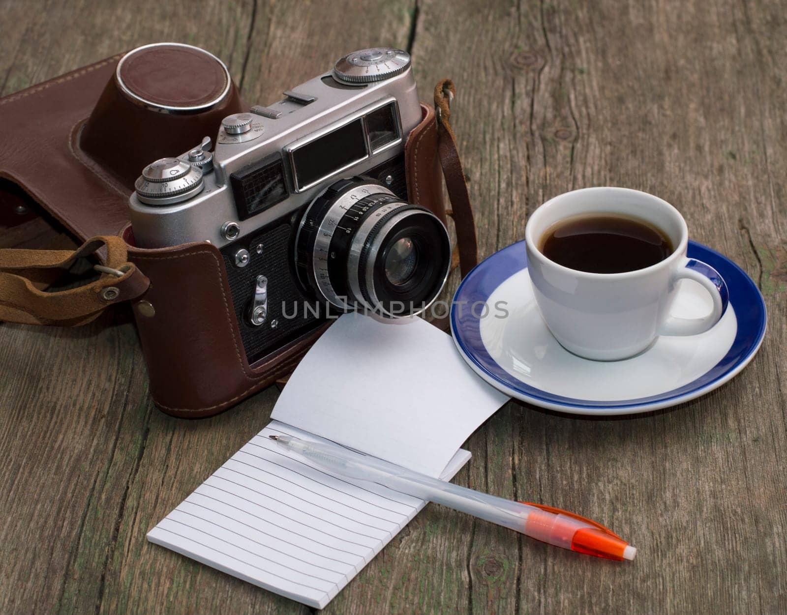 the old camera, coffee and notebook with the handle on a wooden table, a festive card a retro subject